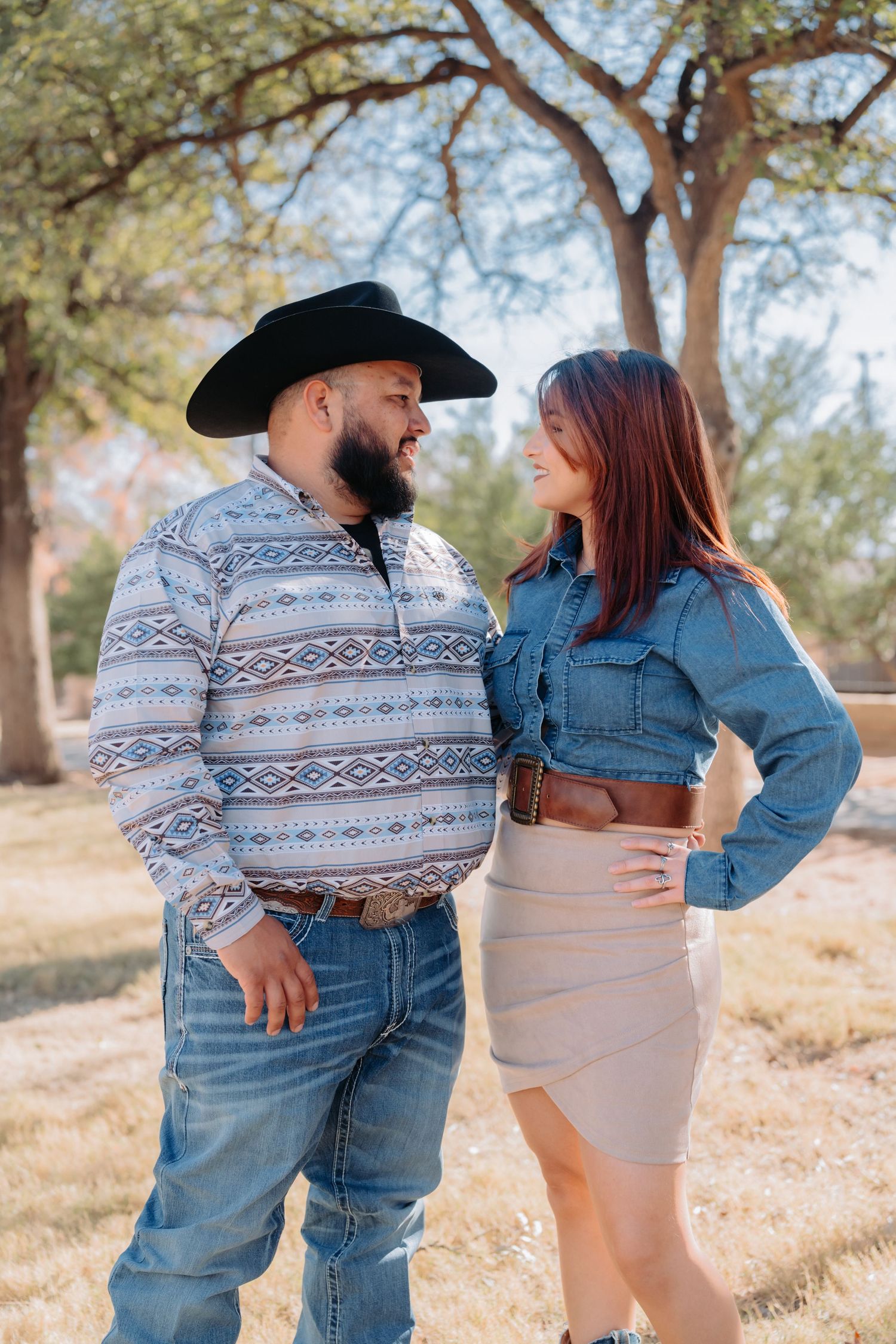 Couple shares playful moments in western outfits during outdoor photo session.