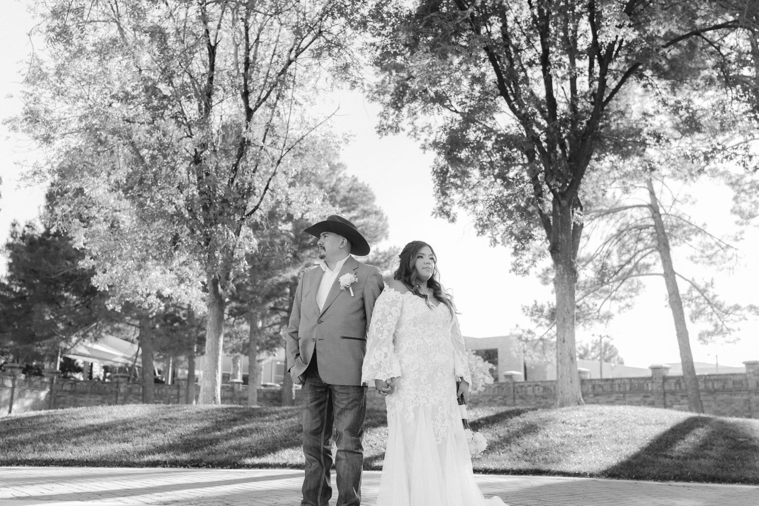 Black and white portrait of wedding couple walking together in park setting.