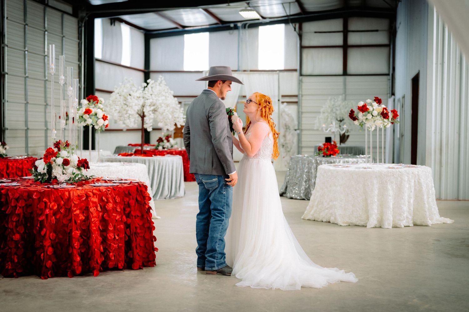 Wide shot of wedding venue decorated with red accents and white drapery.