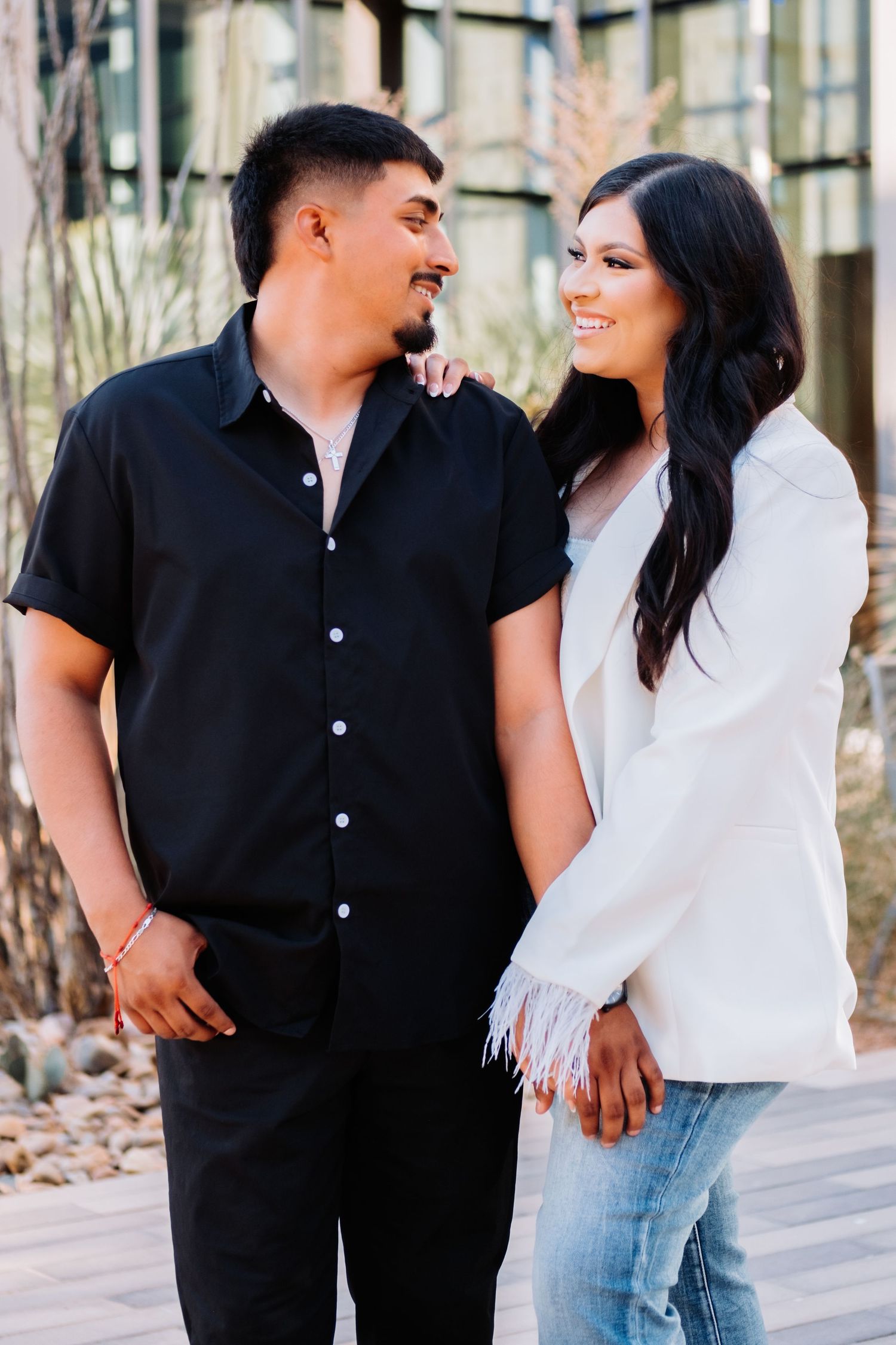 A couple in black and white outfits sharing affectionate moments outdoors.