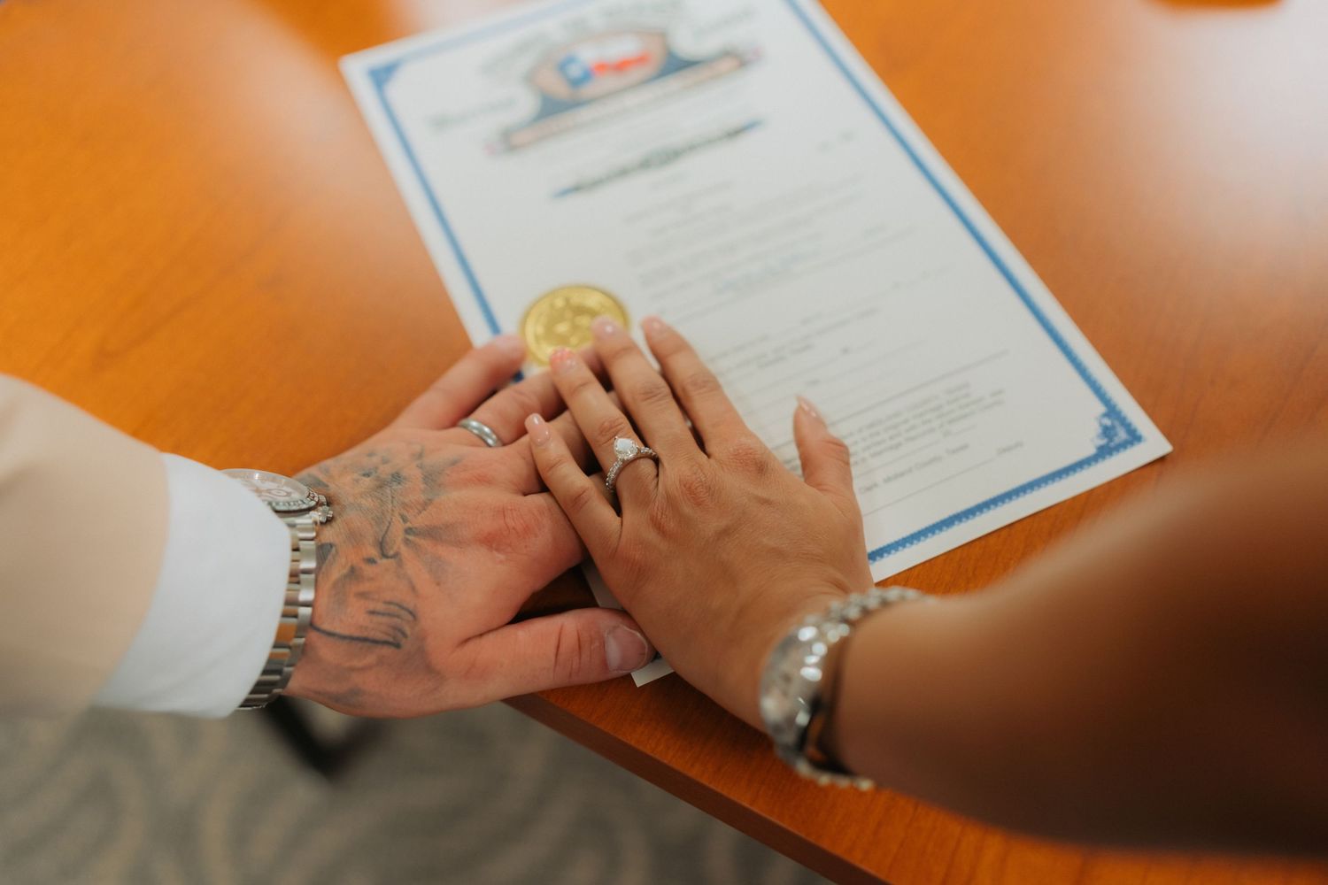 Close-up of hands signing legal documents and paperwork on an orange wooden table surface.