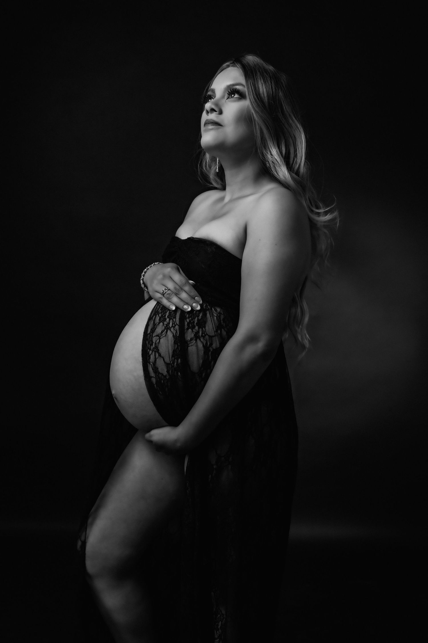 Dramatic black and white maternity photography with artistic poses and moody lighting.