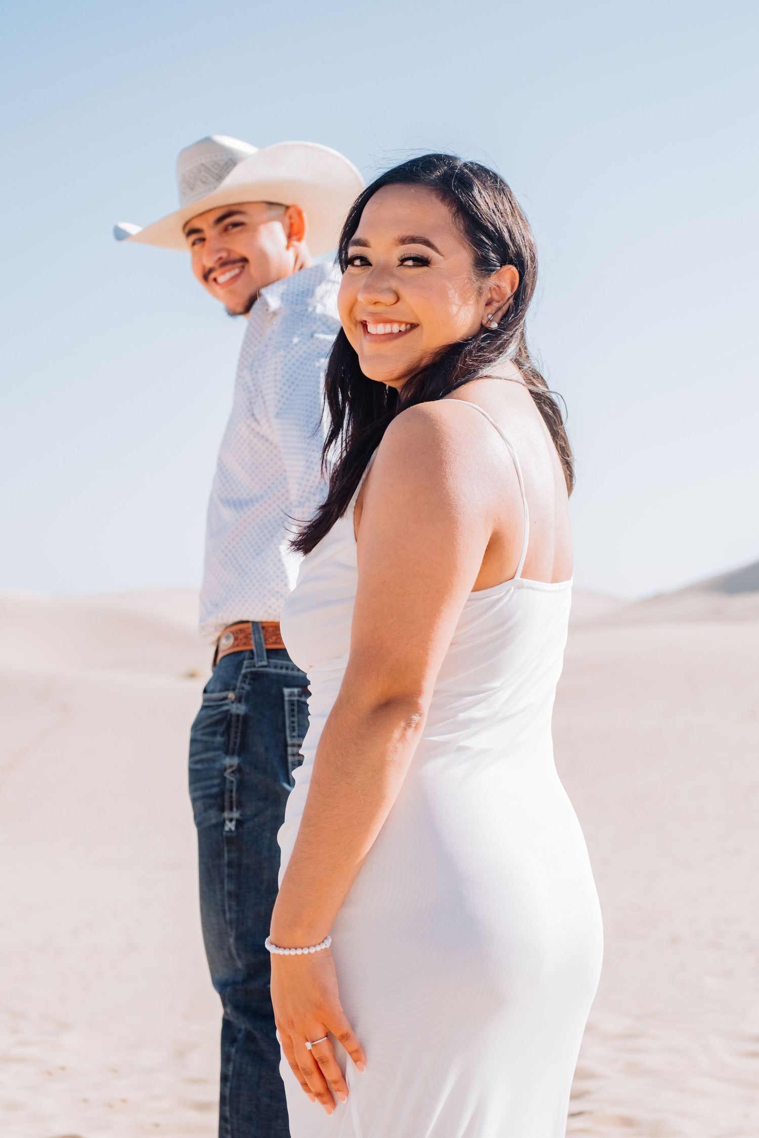Couple shares intimate moments while sitting on desert sand dunes.