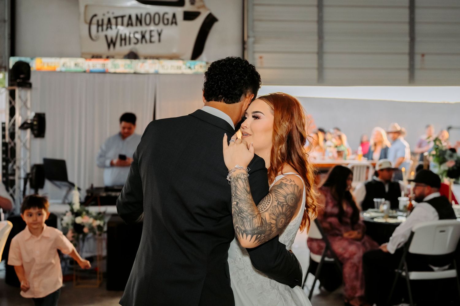 A tender moment during a wedding first dance in an industrial-style reception venue.