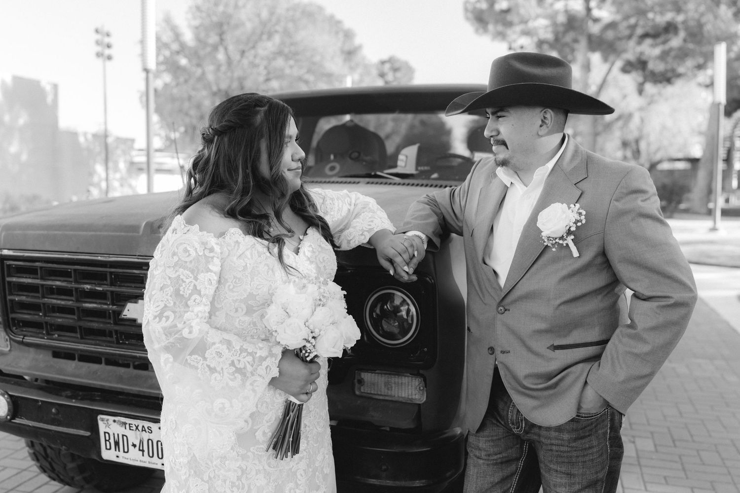 Black and white photo of couple by vintage truck, bride holding bouquet.