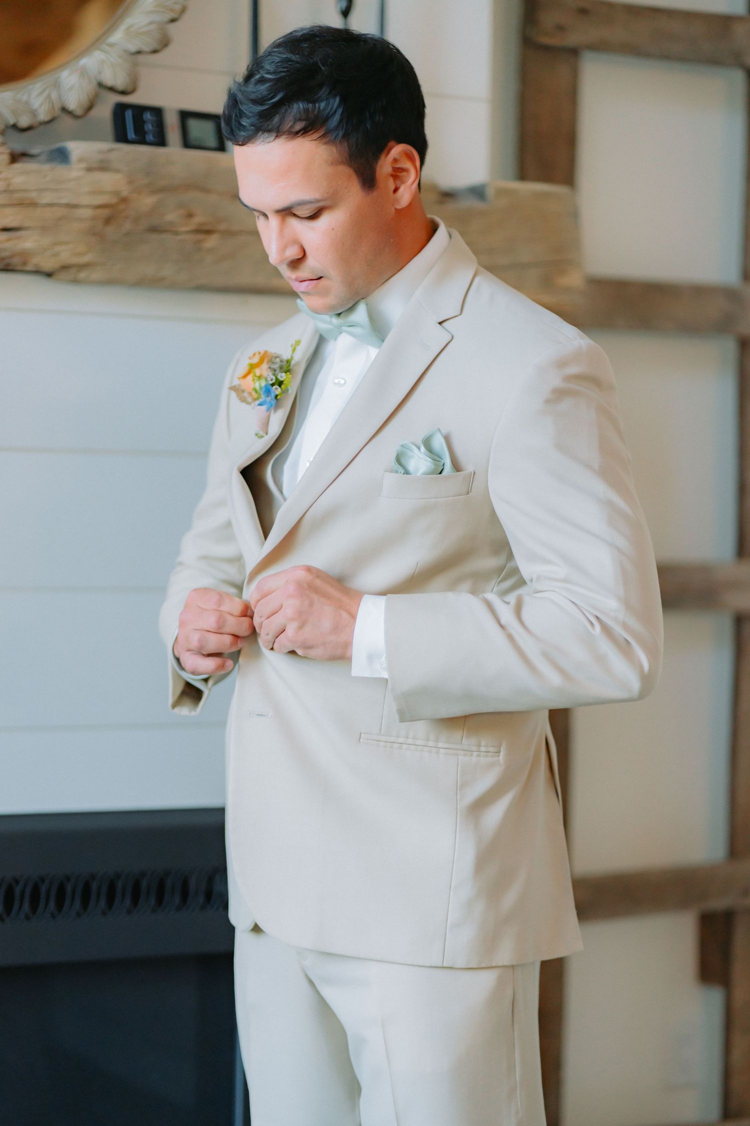 Groom wearing cream colored suit with mint pocket square and boutonniere.