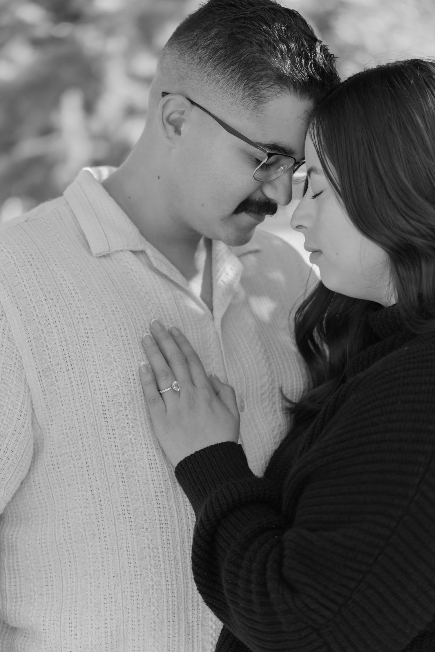 A romantic black and white photo series showing a couple in white and black clothing sharing tender kisses outdoors.