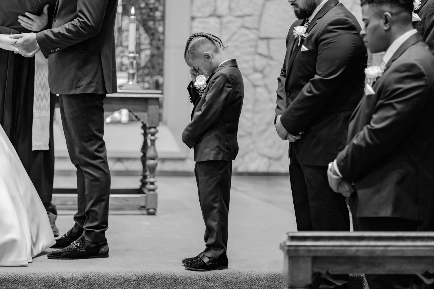 Black and white image of wedding ceremony participants standing at church altar.