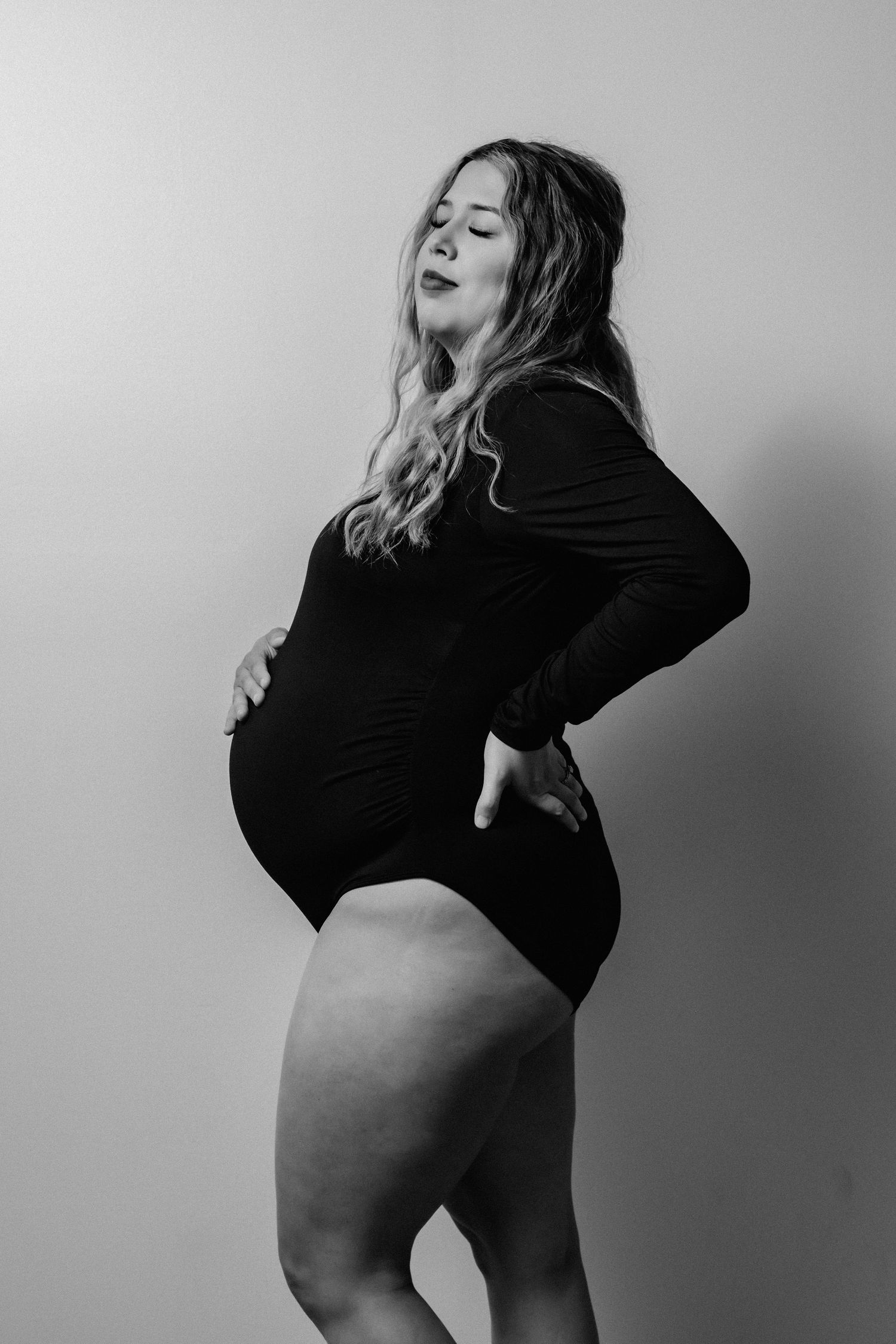 Black and white artistic maternity portrait showcasing pregnant silhouette.