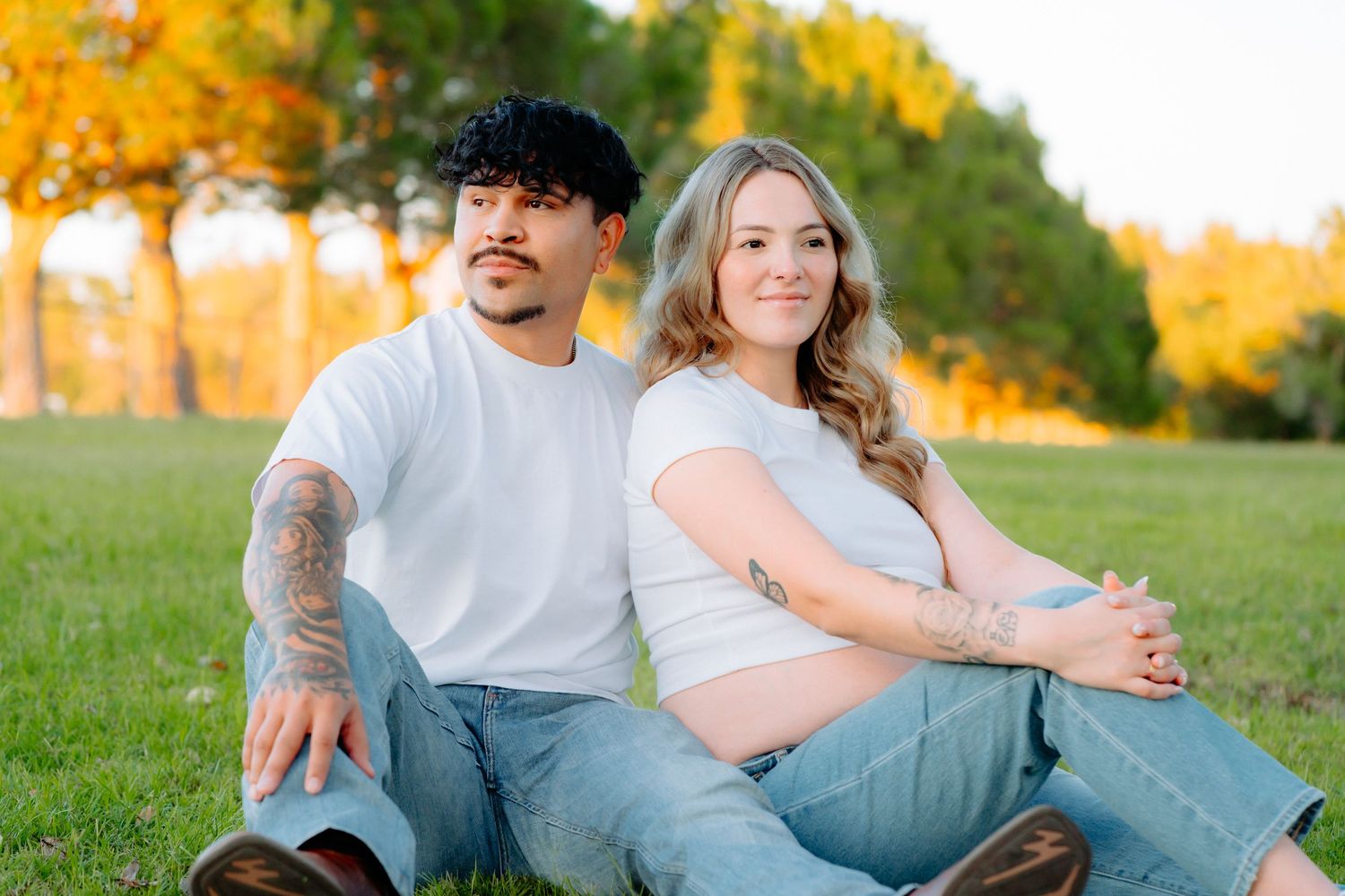 Intimate couple's portrait session in grassy field during sunset with natural lighting.