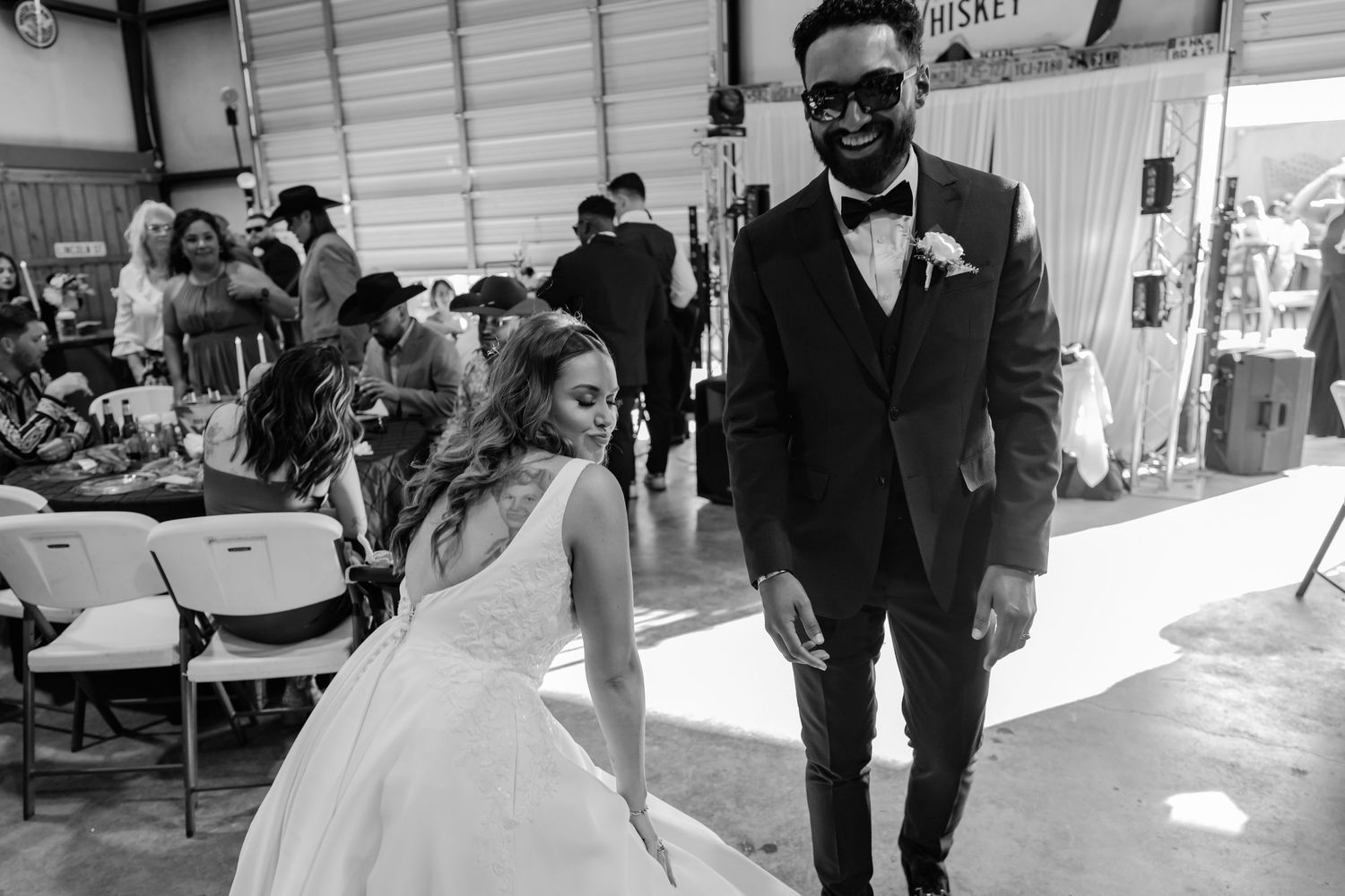 A wedding couple in black and white poses together in a casual venue setting.