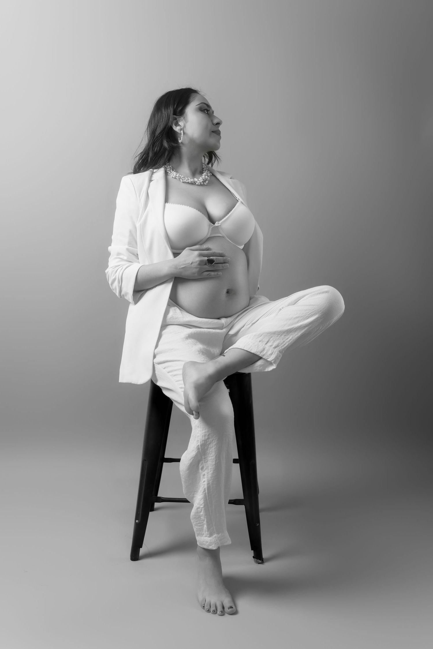 Minimalist black and white maternity portraits featuring relaxed poses on a chair.