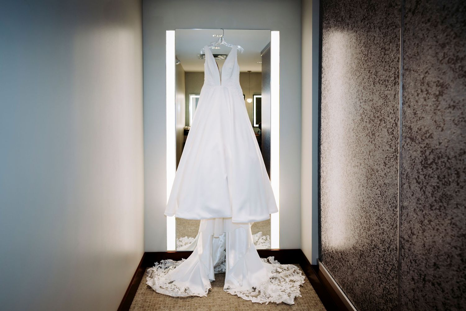 White wedding dress hanging in doorway showing full length and train details.