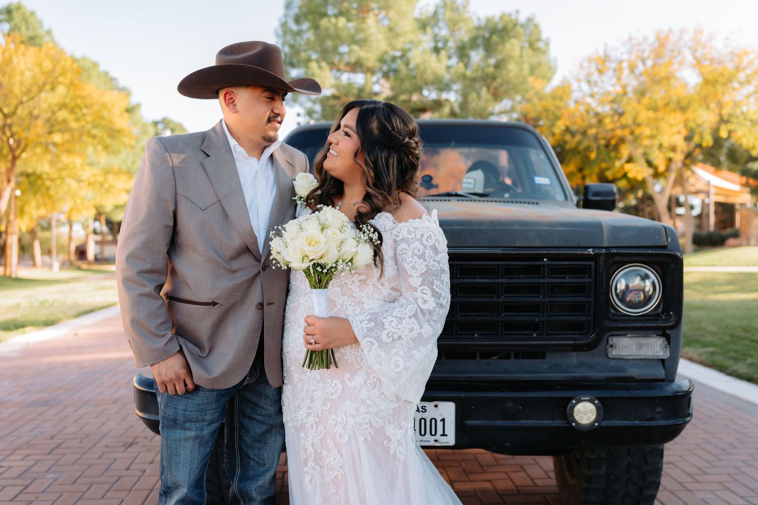A rustic wedding photoshoot with a vintage truck and autumn foliage.
