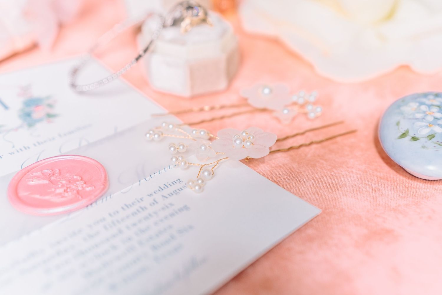 Wedding invitation and decorative elements in soft pink and blue tones on a coral background.