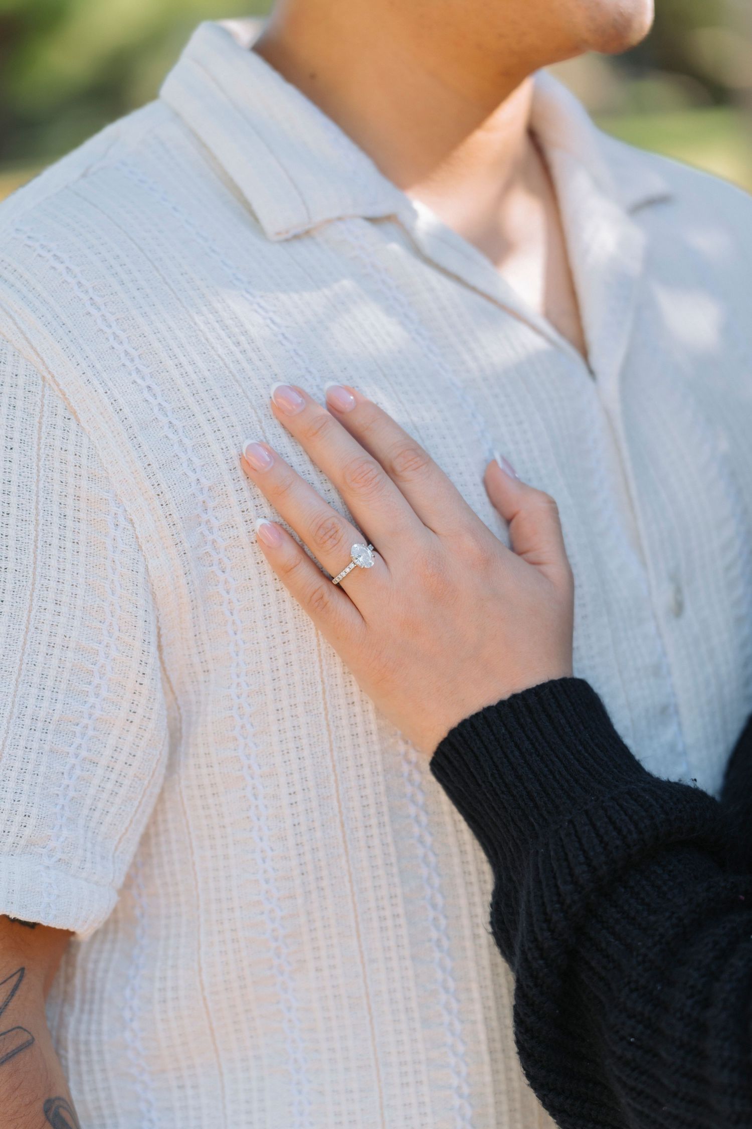 A close-up series showing a hand wearing a black sleeve touching a white textured shirt with delicate details.