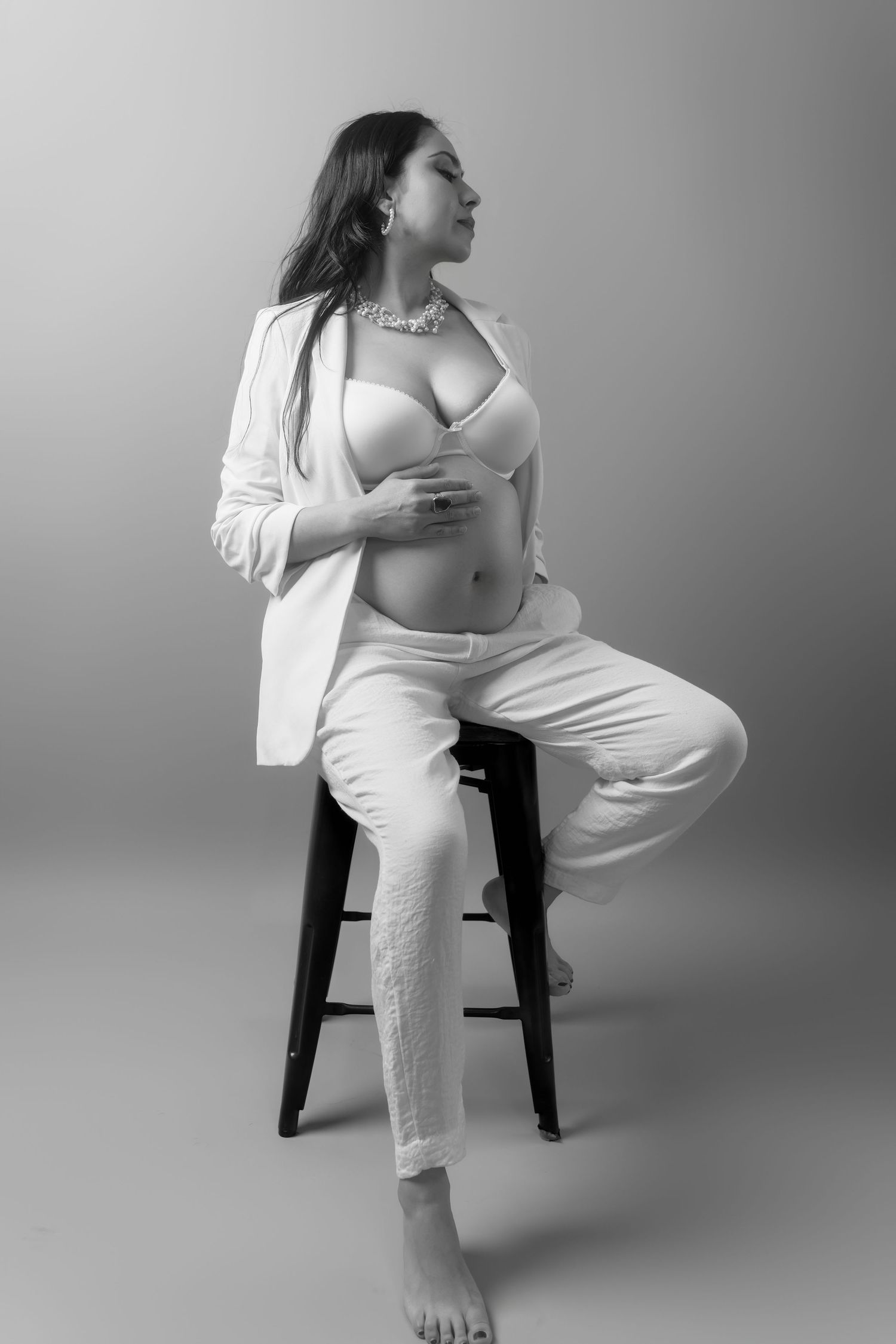 Artistic maternity portraits in white attire showing various seated poses against a gray backdrop.