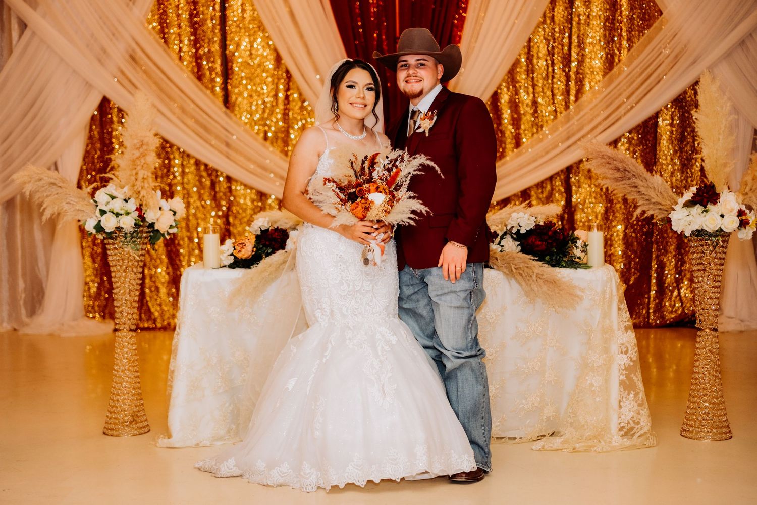 Elegant wedding reception setting with gold sequin backdrop and white draping accents.