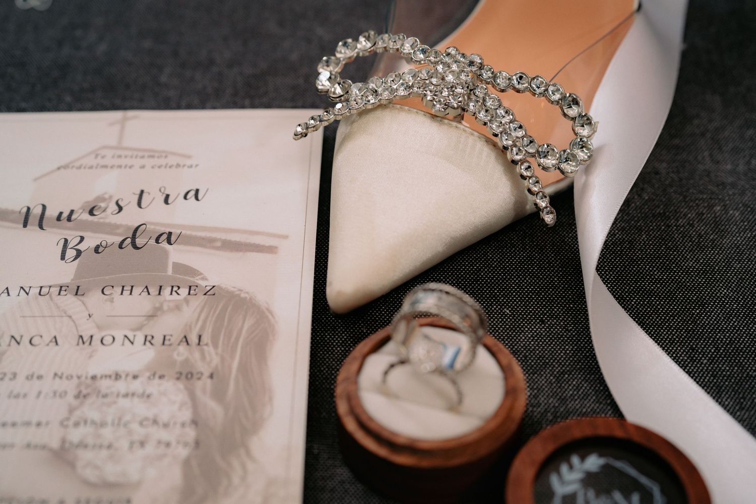 Wedding invitation suite with crystal details and rings on dark background.