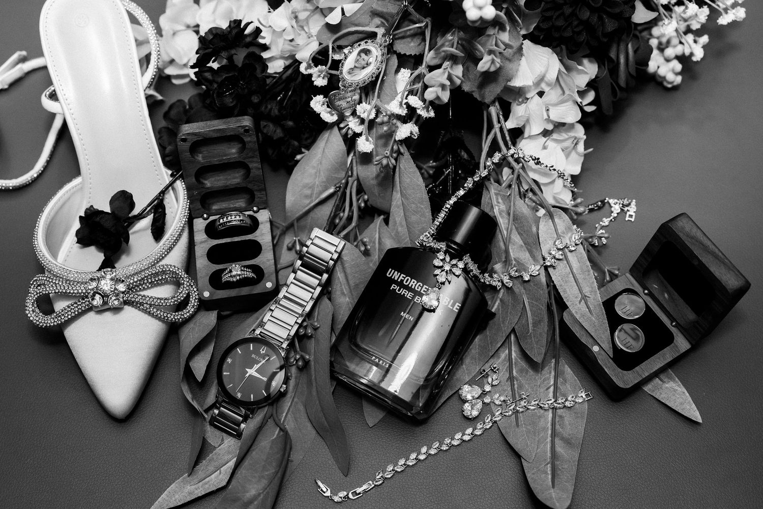 Wedding day accessories including shoes, jewelry and perfume arranged on dark surface.