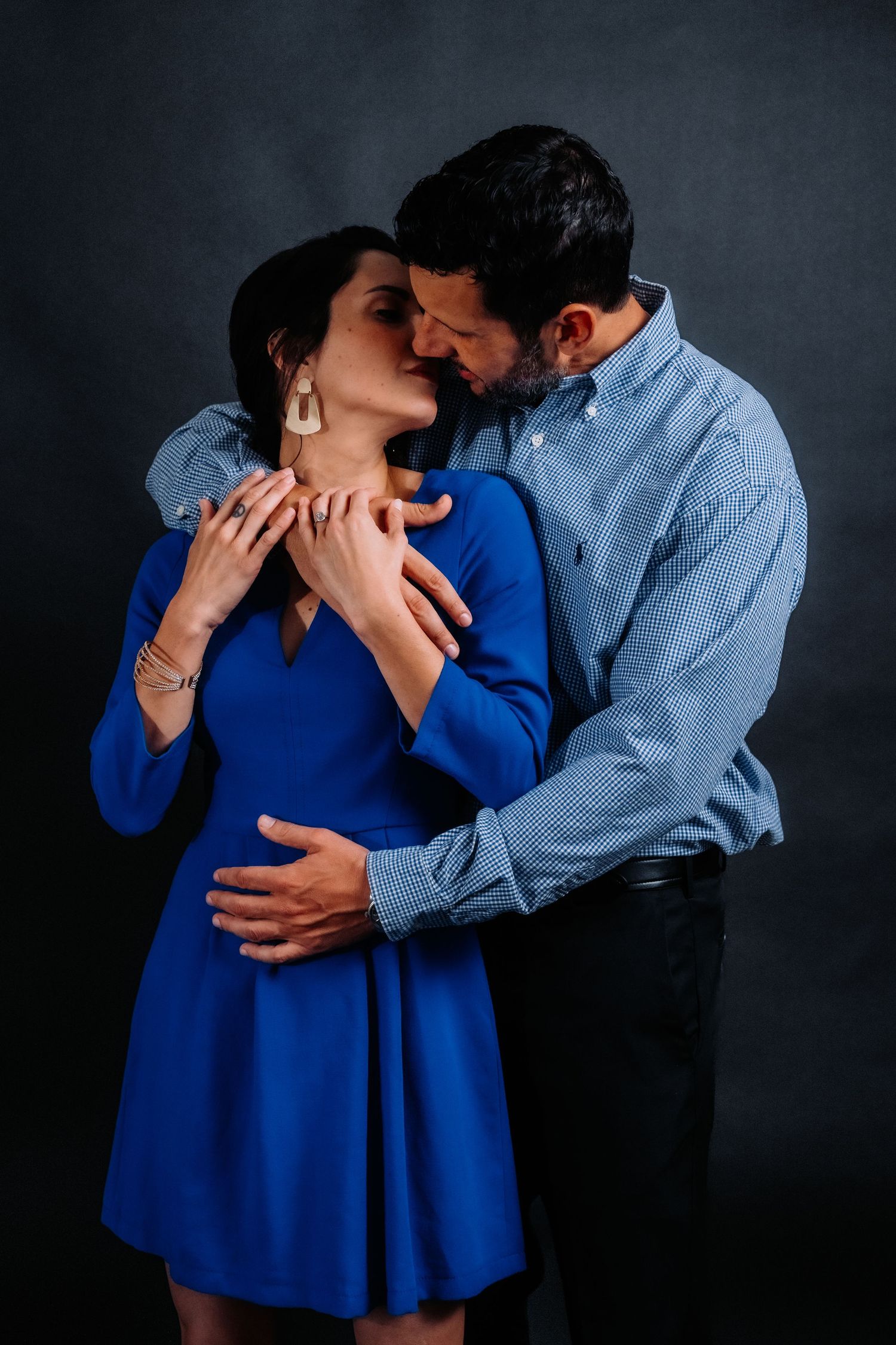 Couple sharing tender moment with woman in royal blue dress and man in light denim shirt.