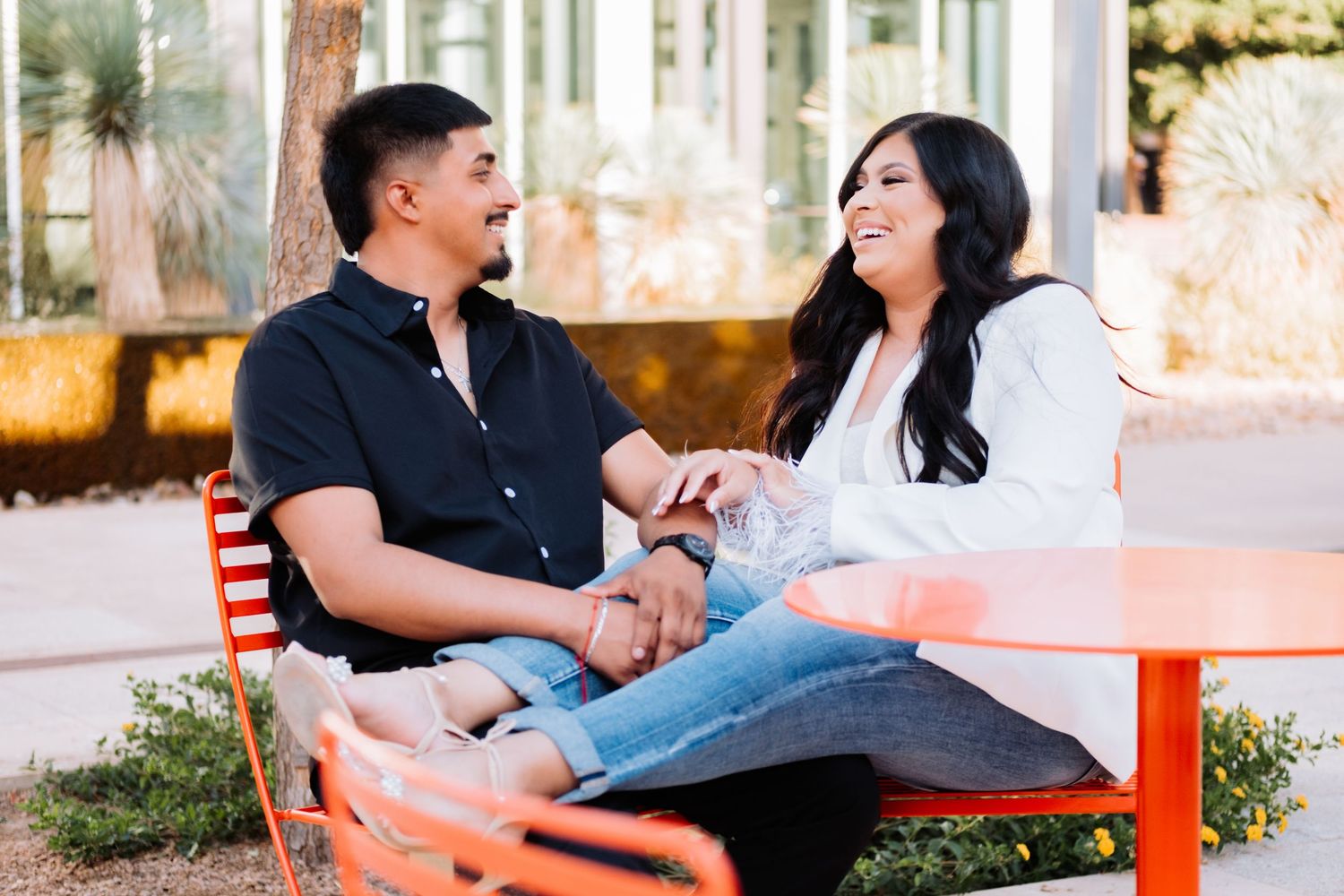 A romantic couple shares intimate moments together on an orange bench in an outdoor setting.