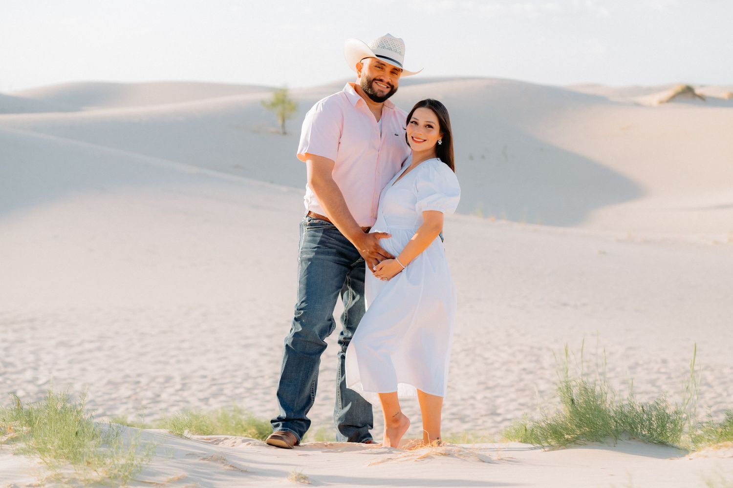 Couple shares intimate moment during desert maternity photoshoot.