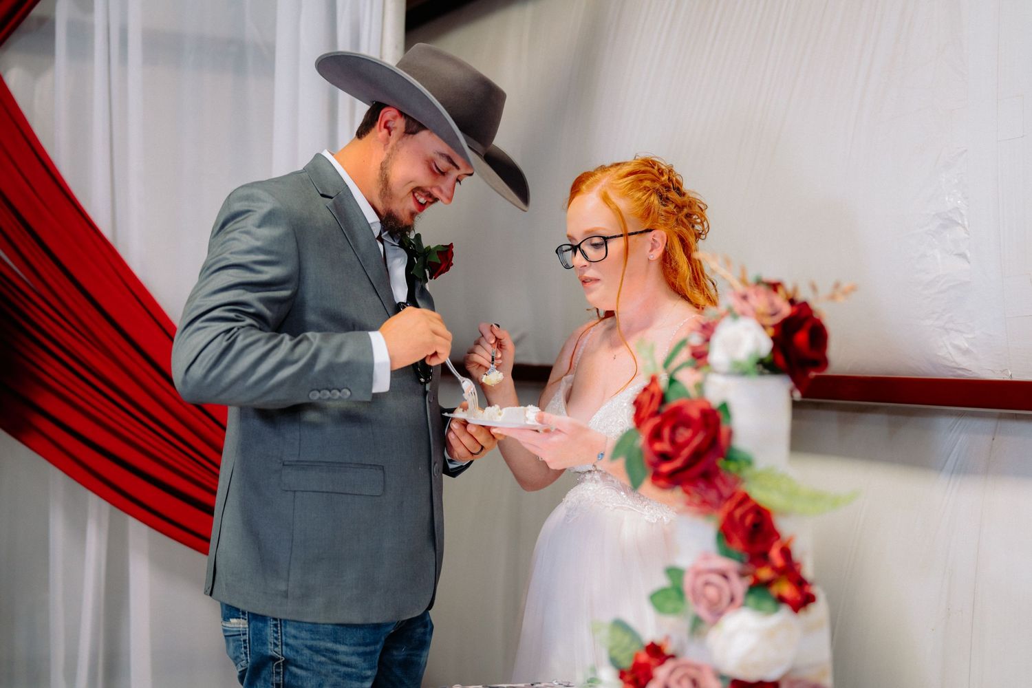 Romantic first dance moment in a wedding venue decorated with red and white accents.