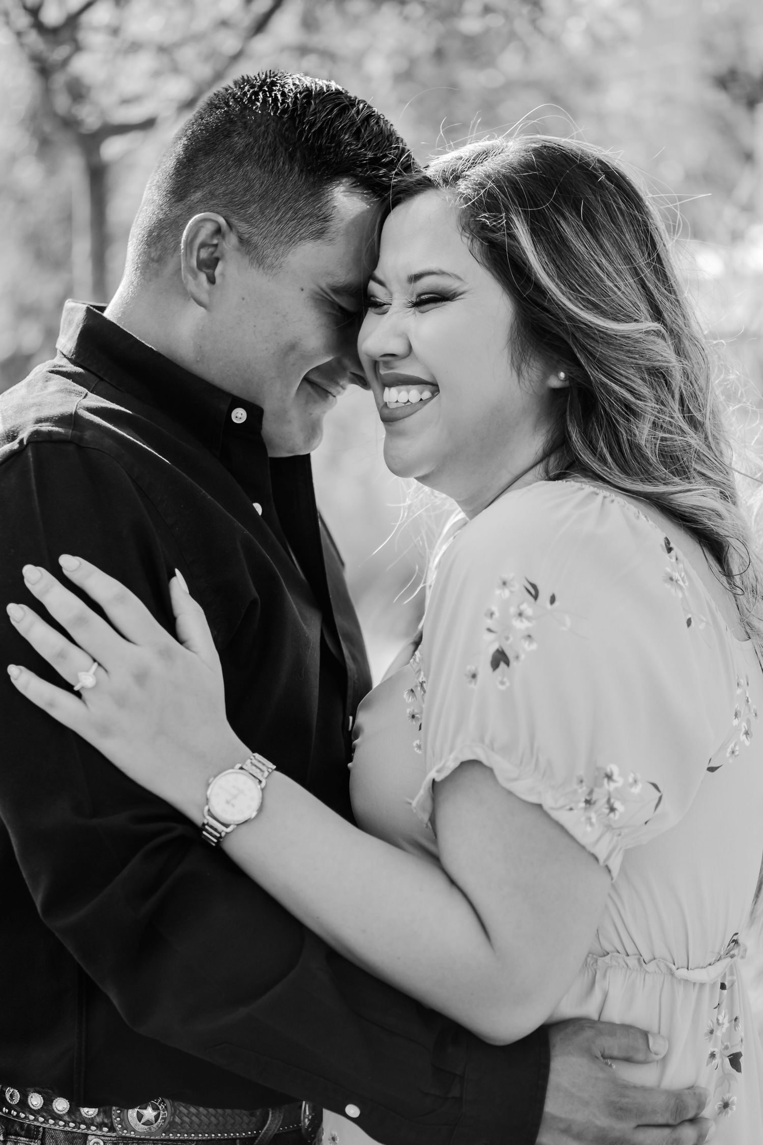 Black and white portrait of laughing couple in intimate embrace outdoors.