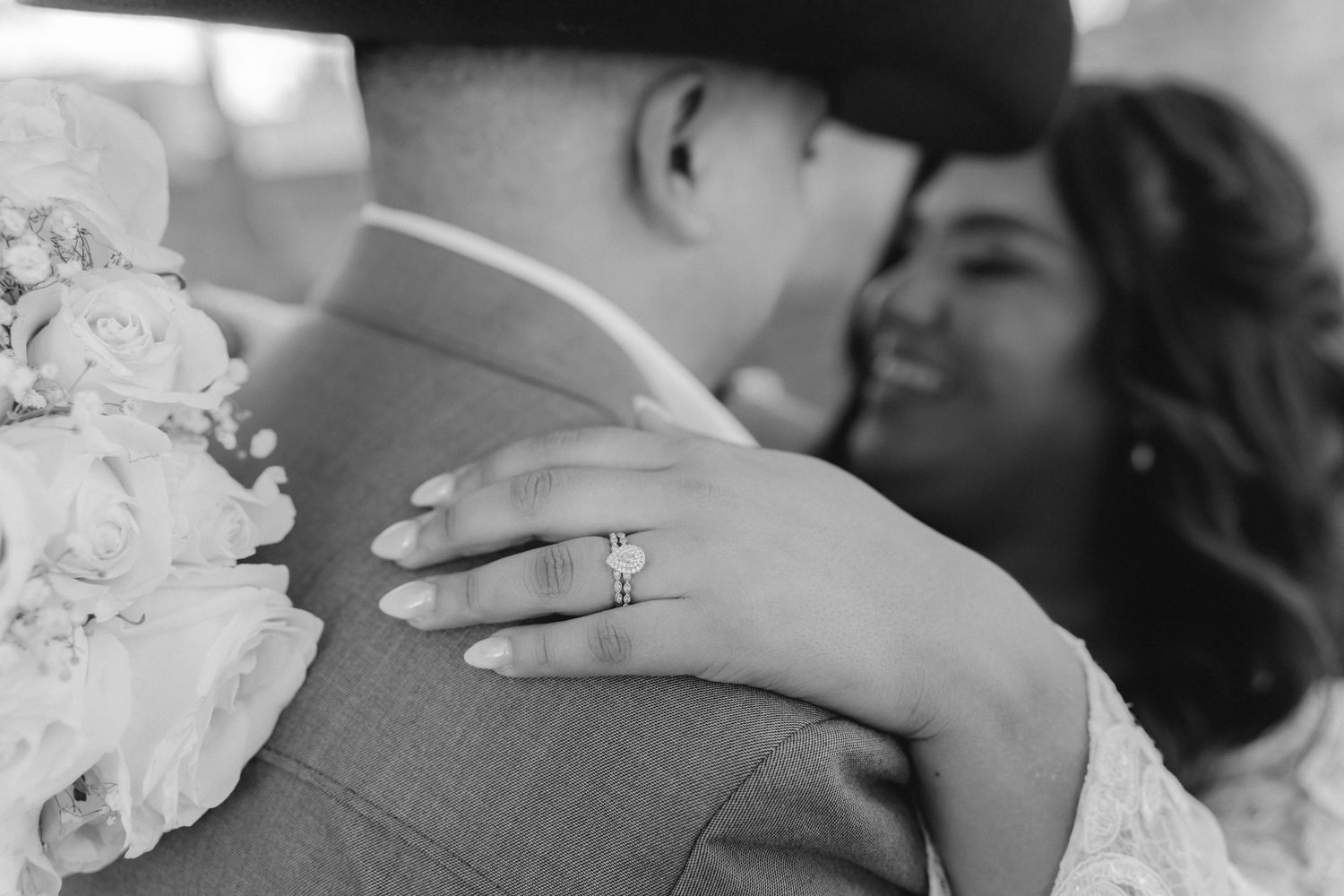 Black and white close-up of couple embracing, showing off wedding ring detail.