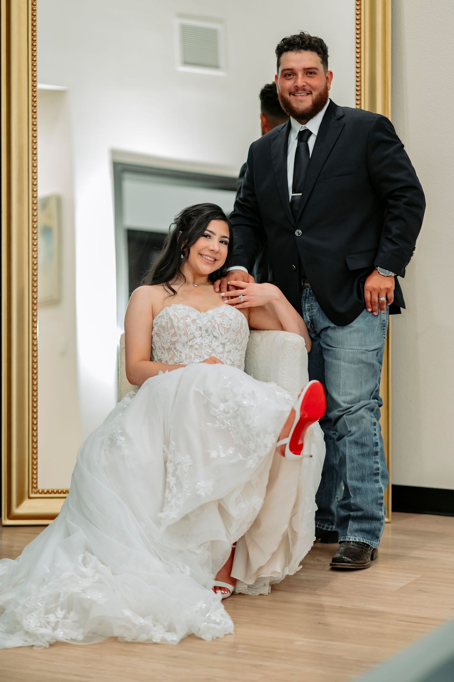 A couple poses together in a hallway, with the bride wearing a white lace wedding dress.