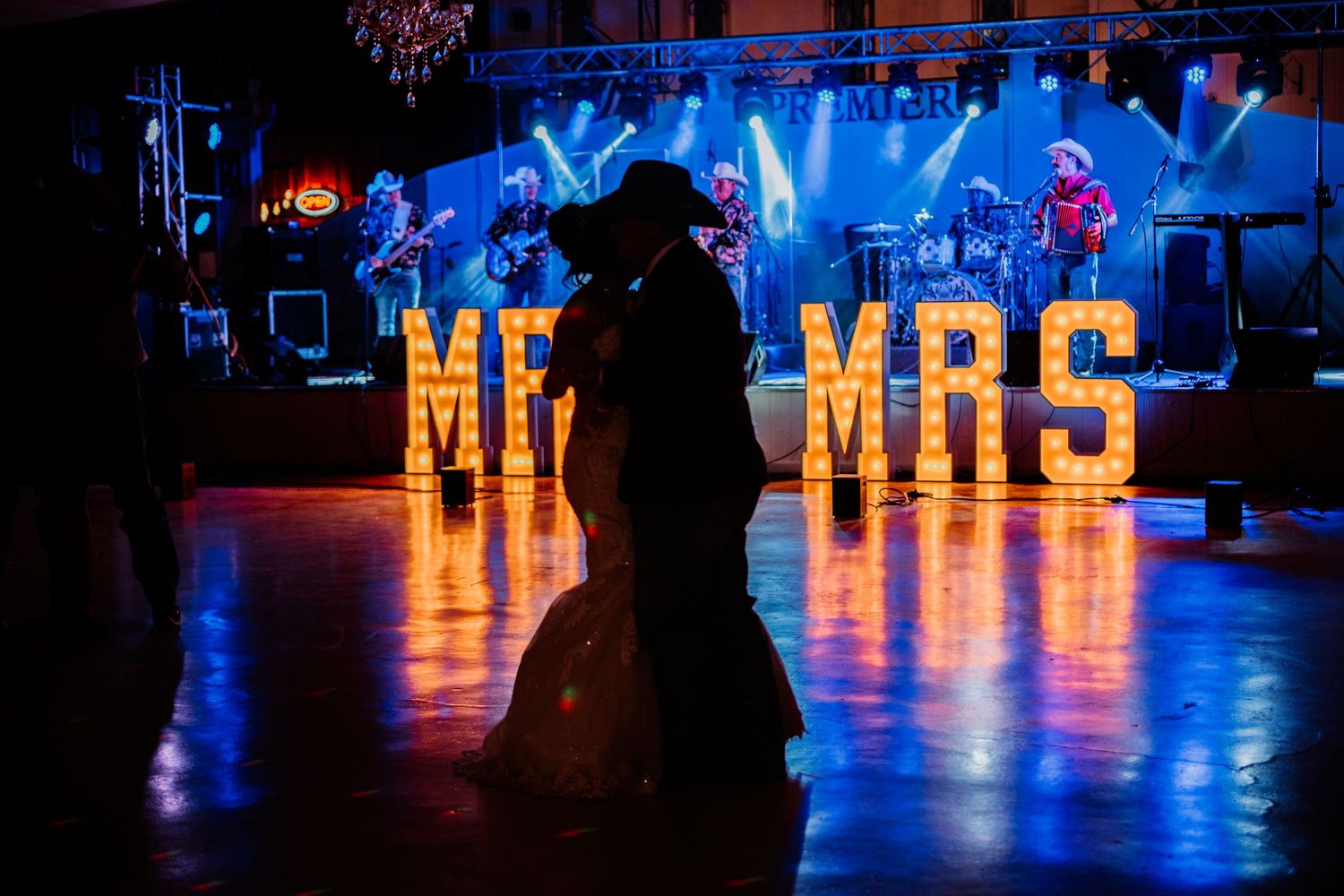 Wedding reception venue with blue uplighting and illuminated 'MR & MRS' sign.