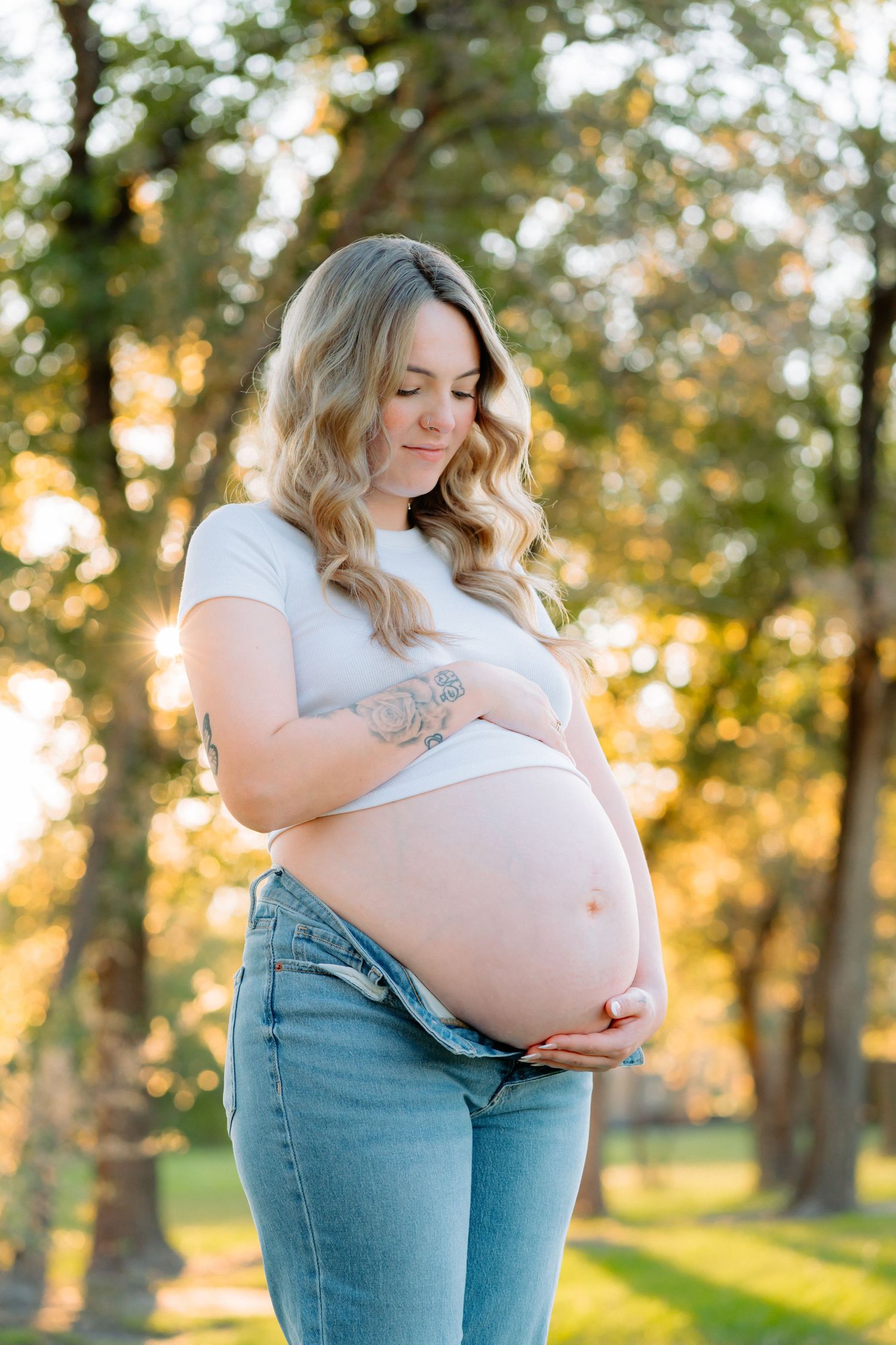 Tender maternity moments captured in a park during golden hour.