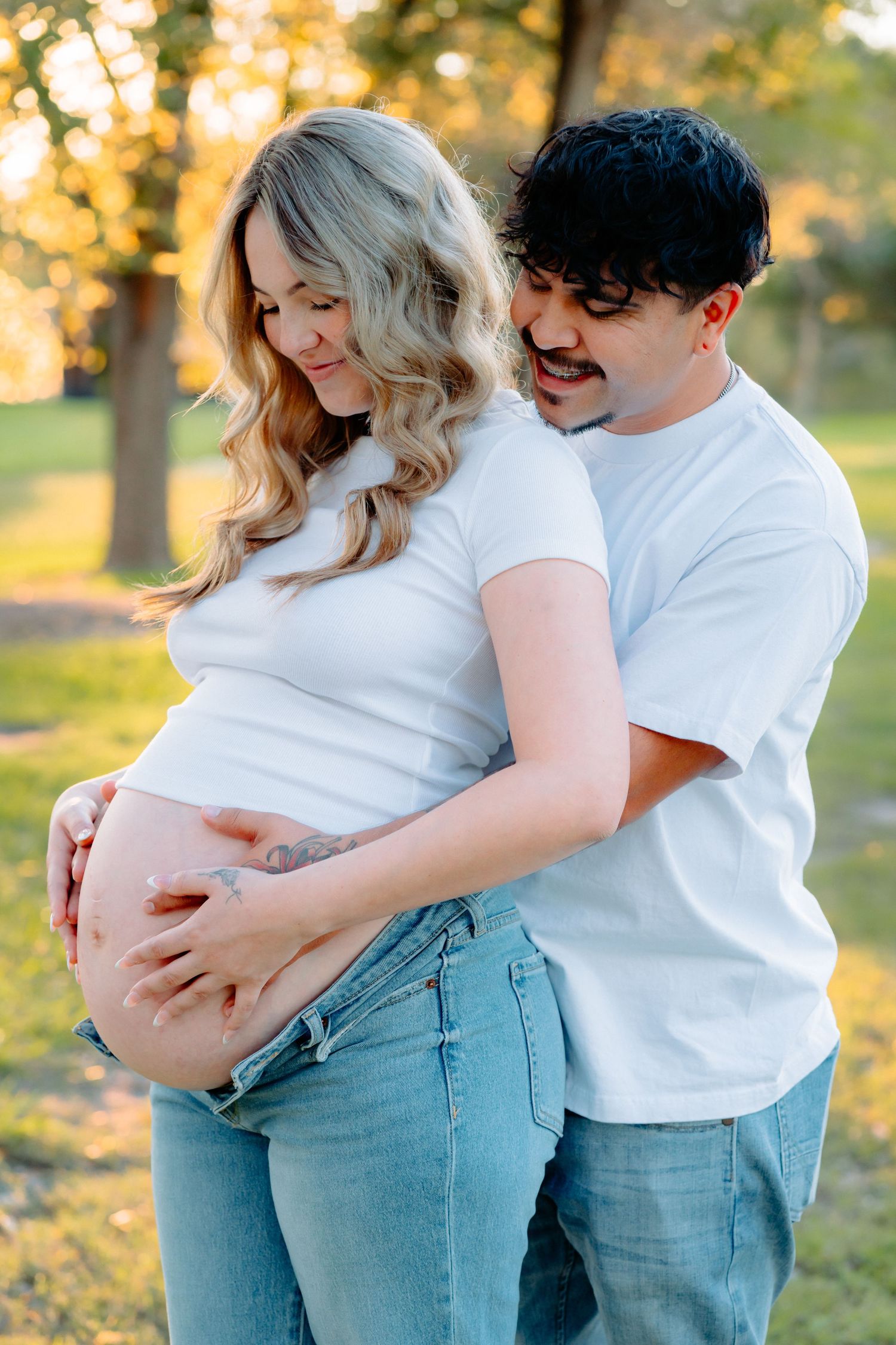 Sweet couple's maternity photos taken in a park at sunset.