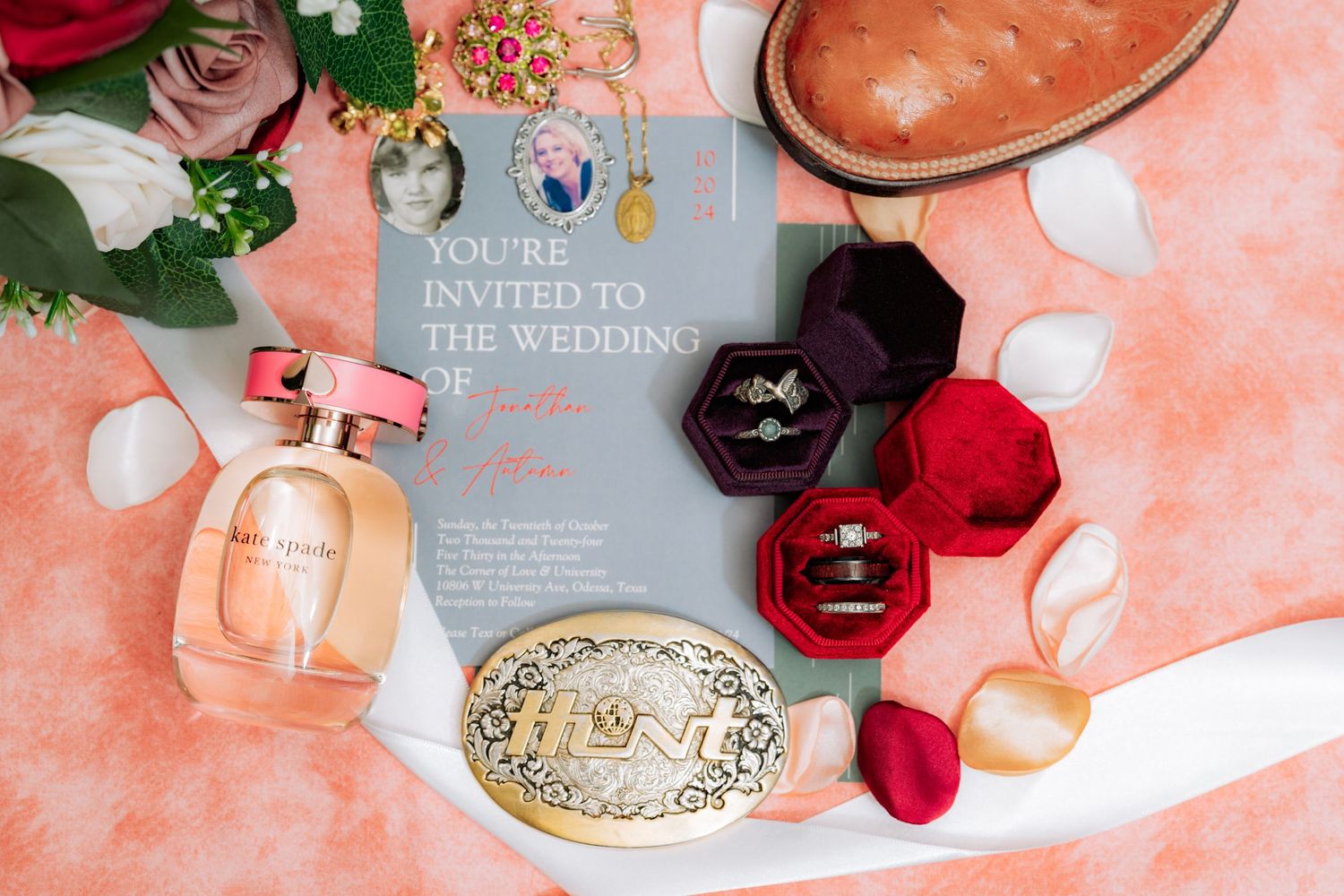 Flat lay of wedding stationery with red roses and decorative elements on a peach colored surface.