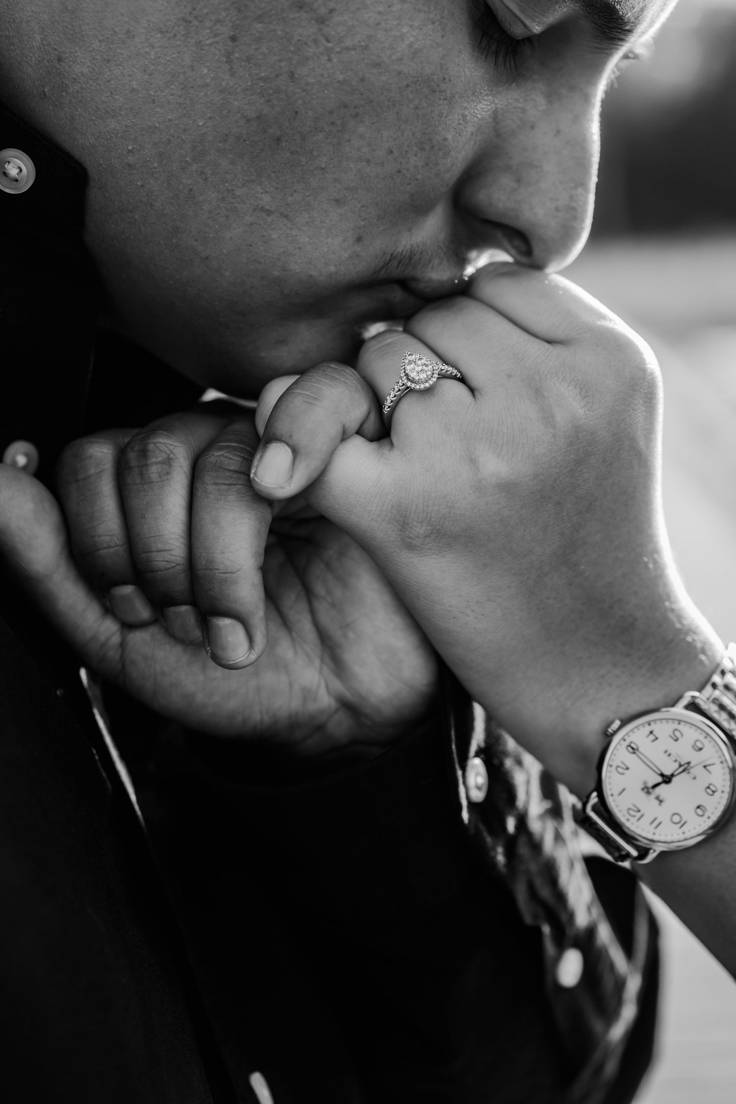 Close-up black and white photo showing hands with engagement ring and tender moment.