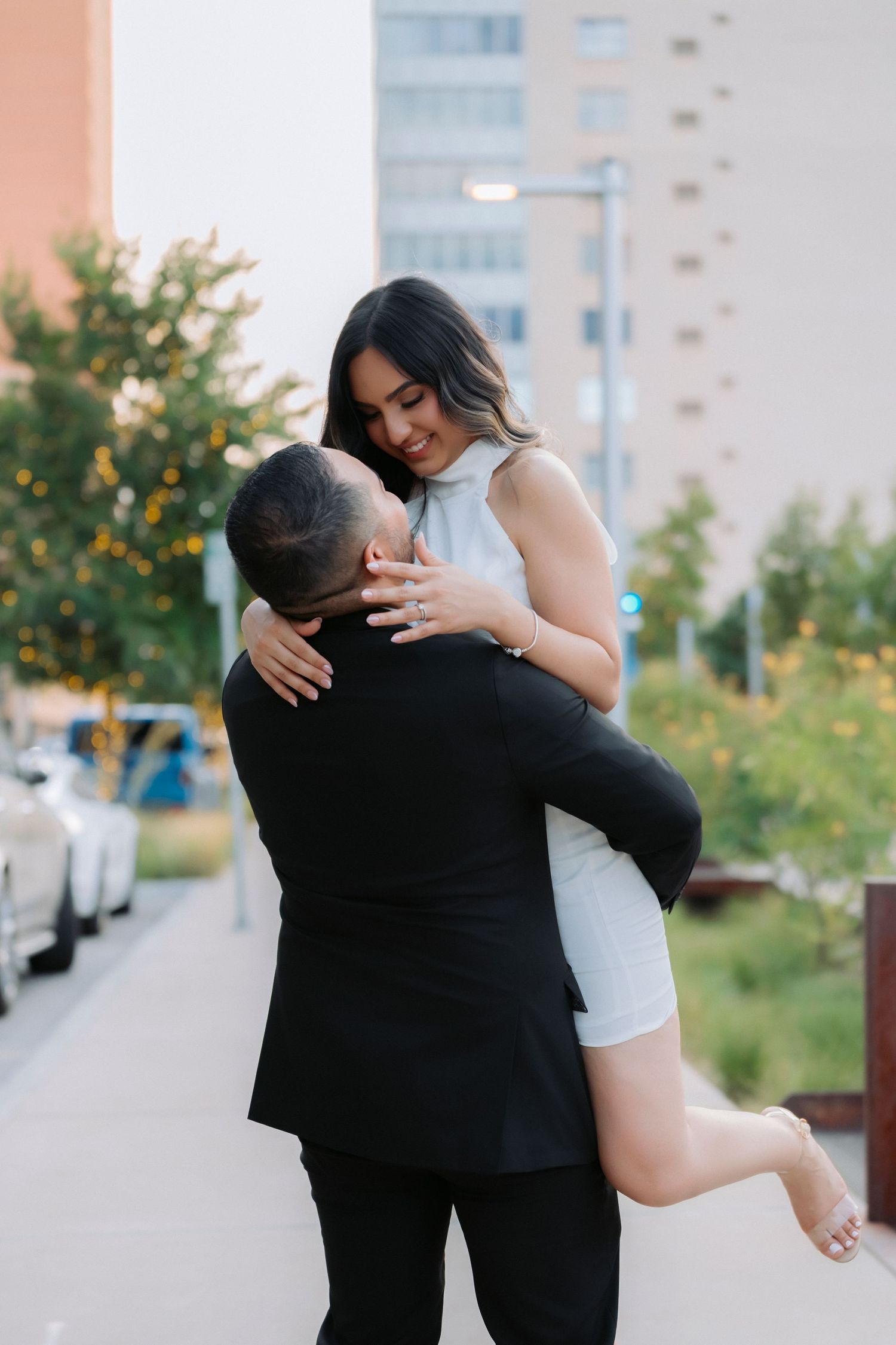 A romantic couple embraces outdoors in a series of candid shots showing affection and joy against an urban backdrop.