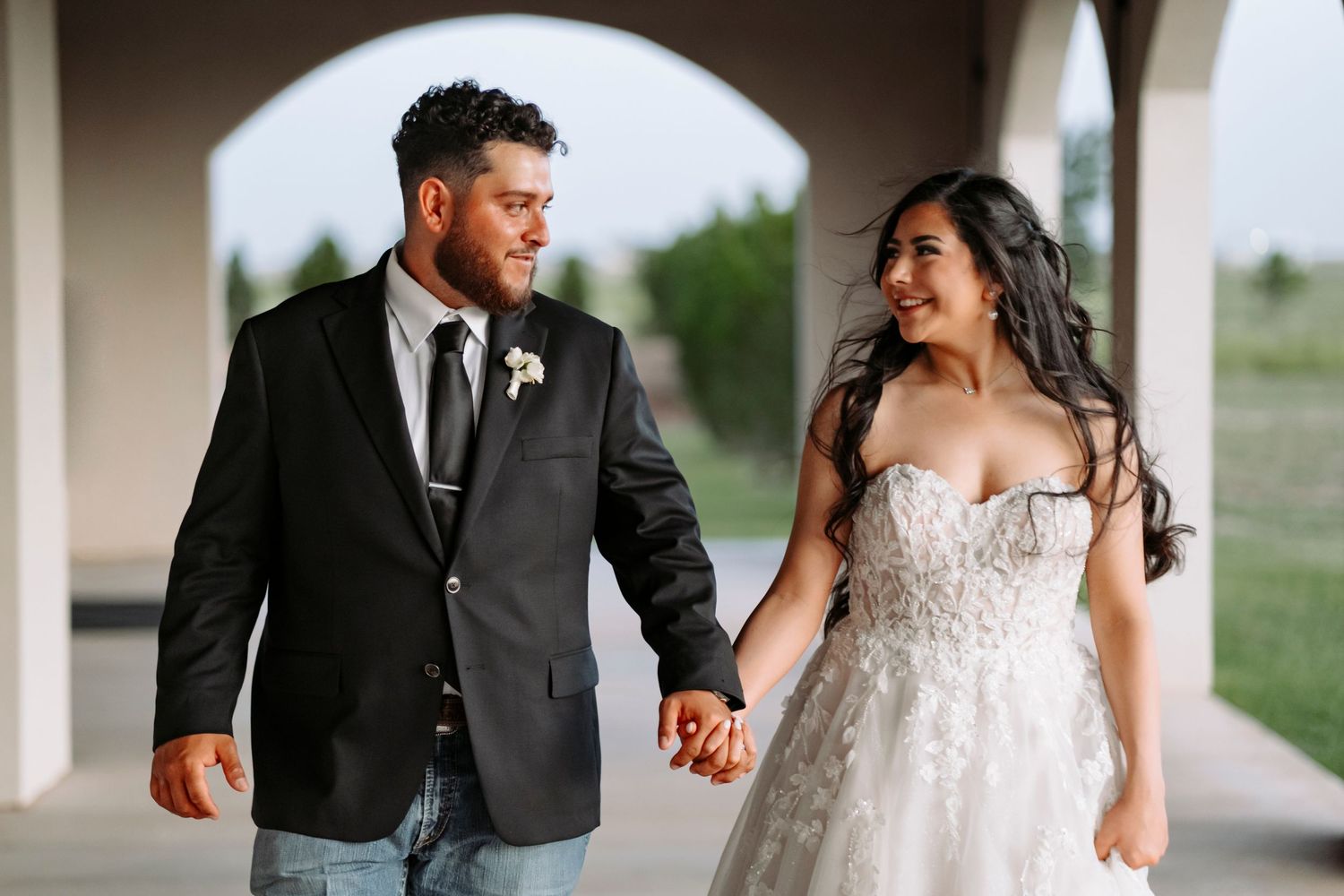 Happy couple walking and laughing together under covered outdoor walkway at wedding venue.