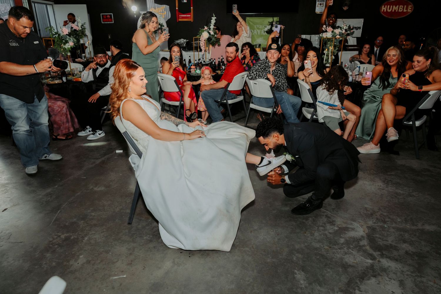 A wedding reception dance captured in a casual indoor venue with guests watching.