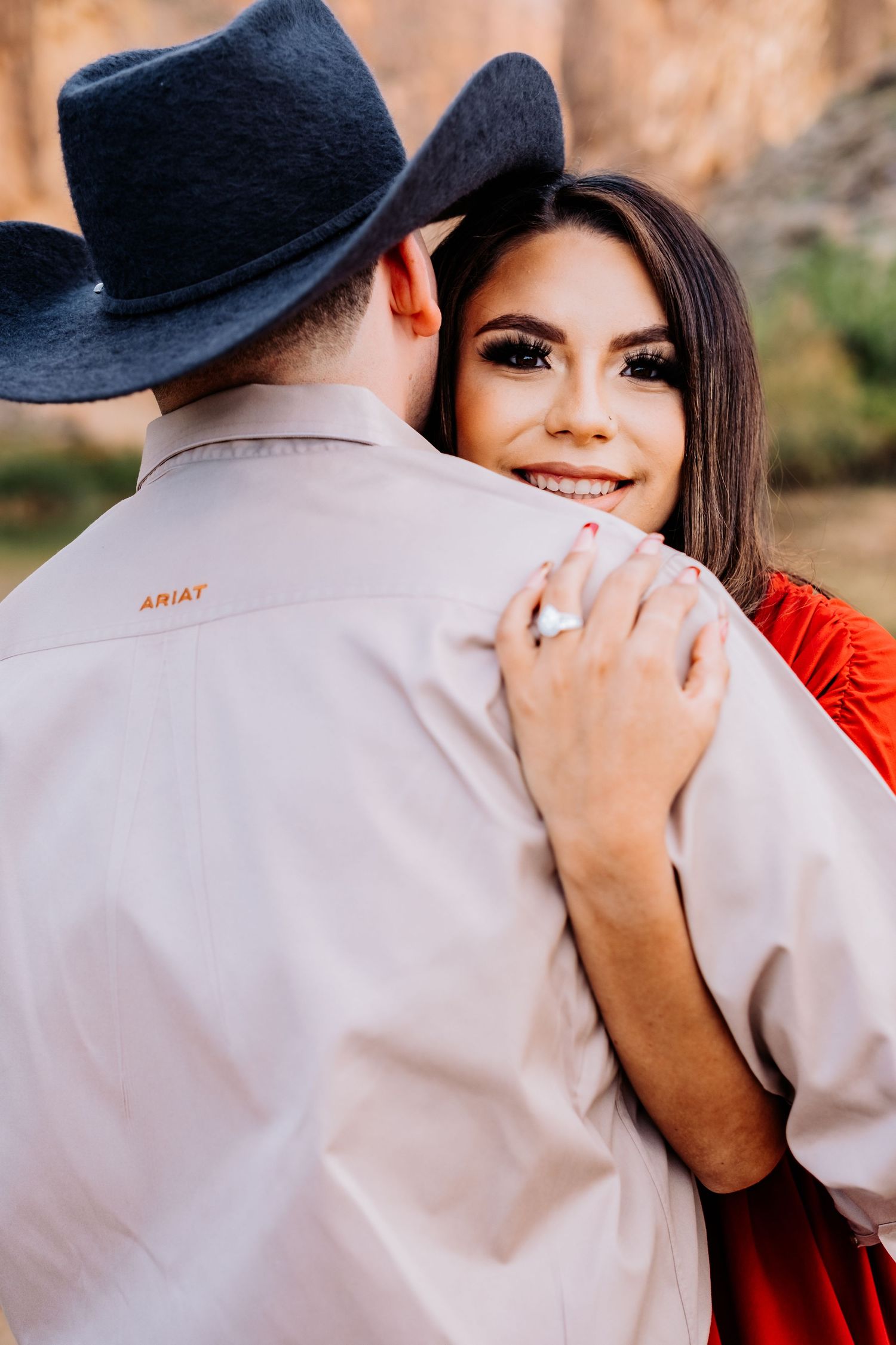A couple in western wear shares an intimate moment against a desert backdrop.