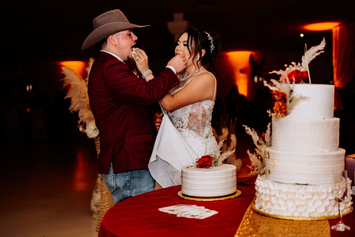 Wedding cake cutting celebration with warm amber lighting and festive atmosphere.