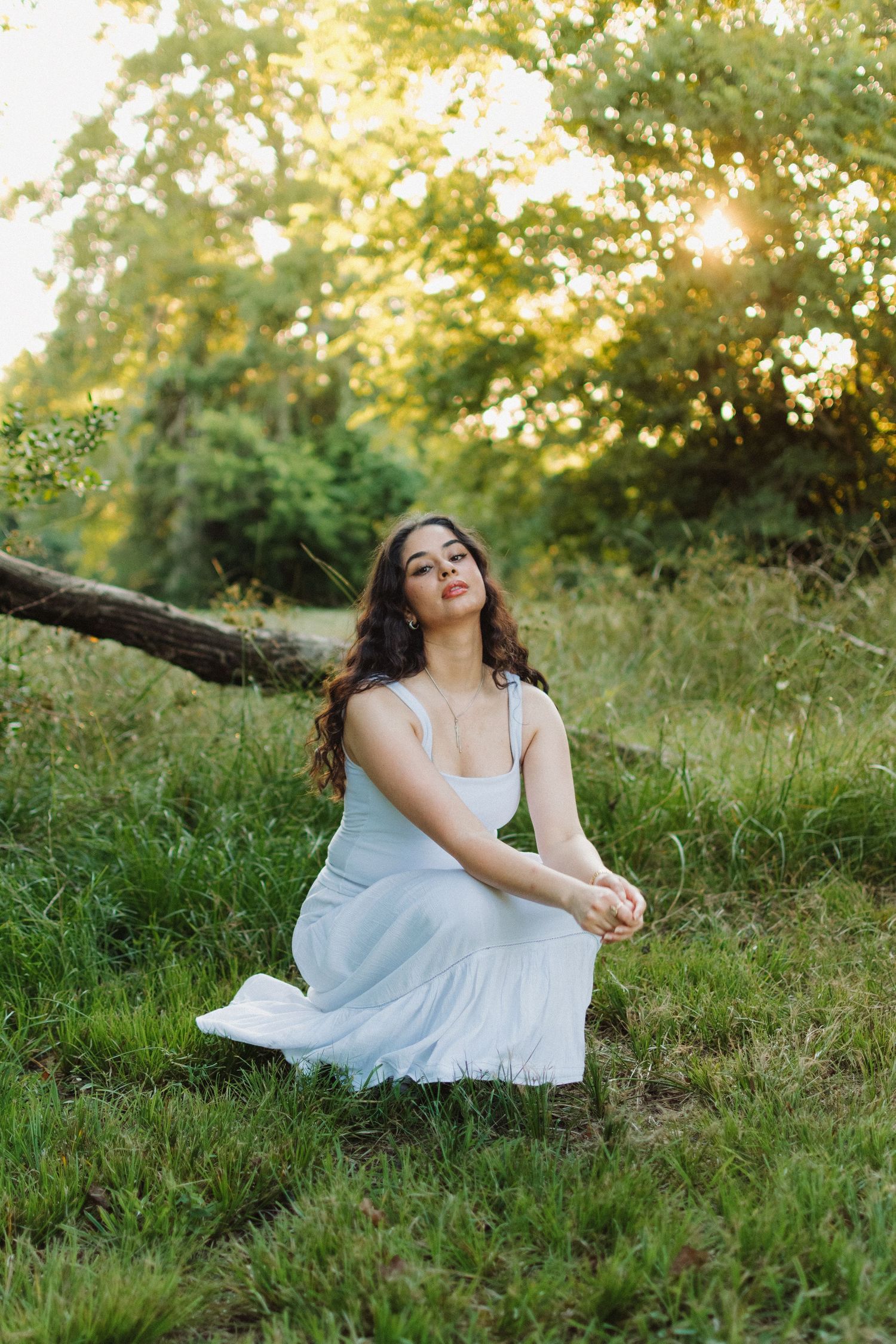 Girl sitting in a field with soft sunlight.