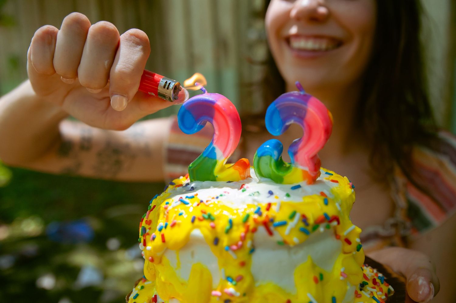 Colorful donut close-up being held up against wooden fence.