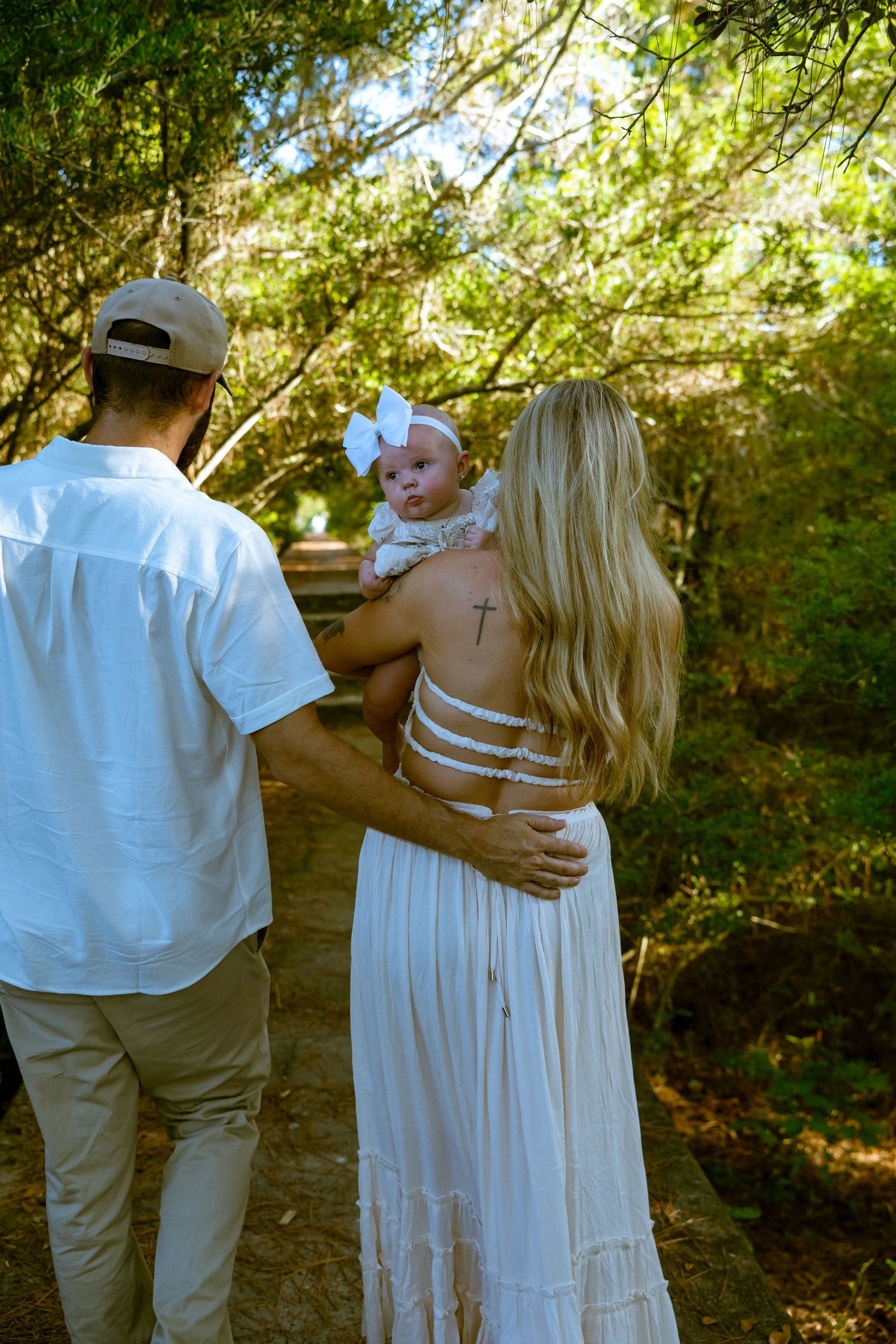 A family walking together through a sunlit wooded area.