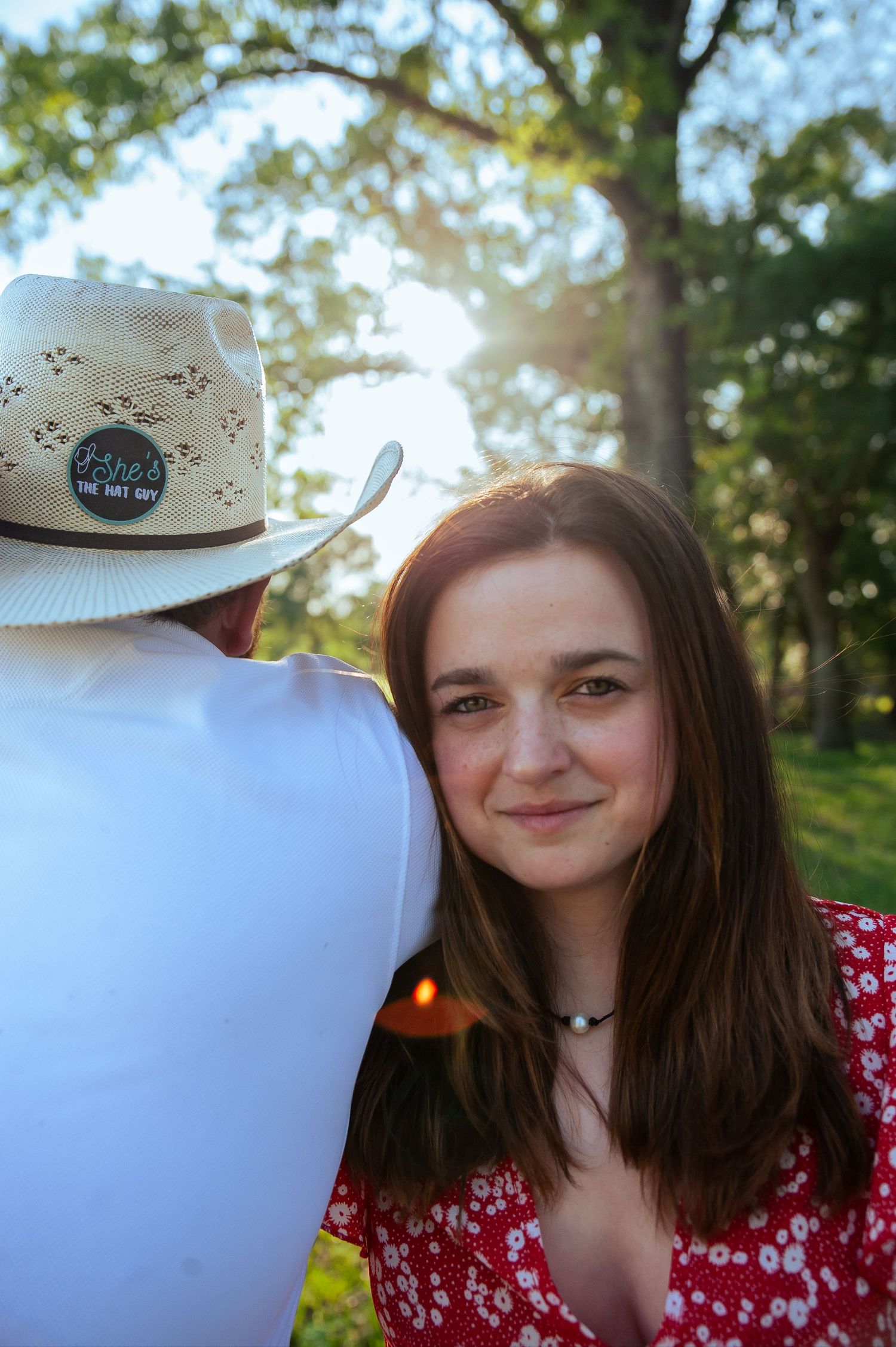 A summer portrait in a park with a white cowboy hat visible in the background.