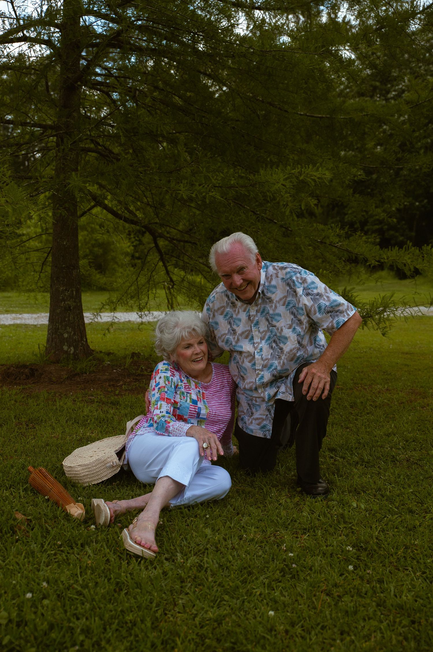 A playful moment captured of two people in matching floral prints sitting on grass.