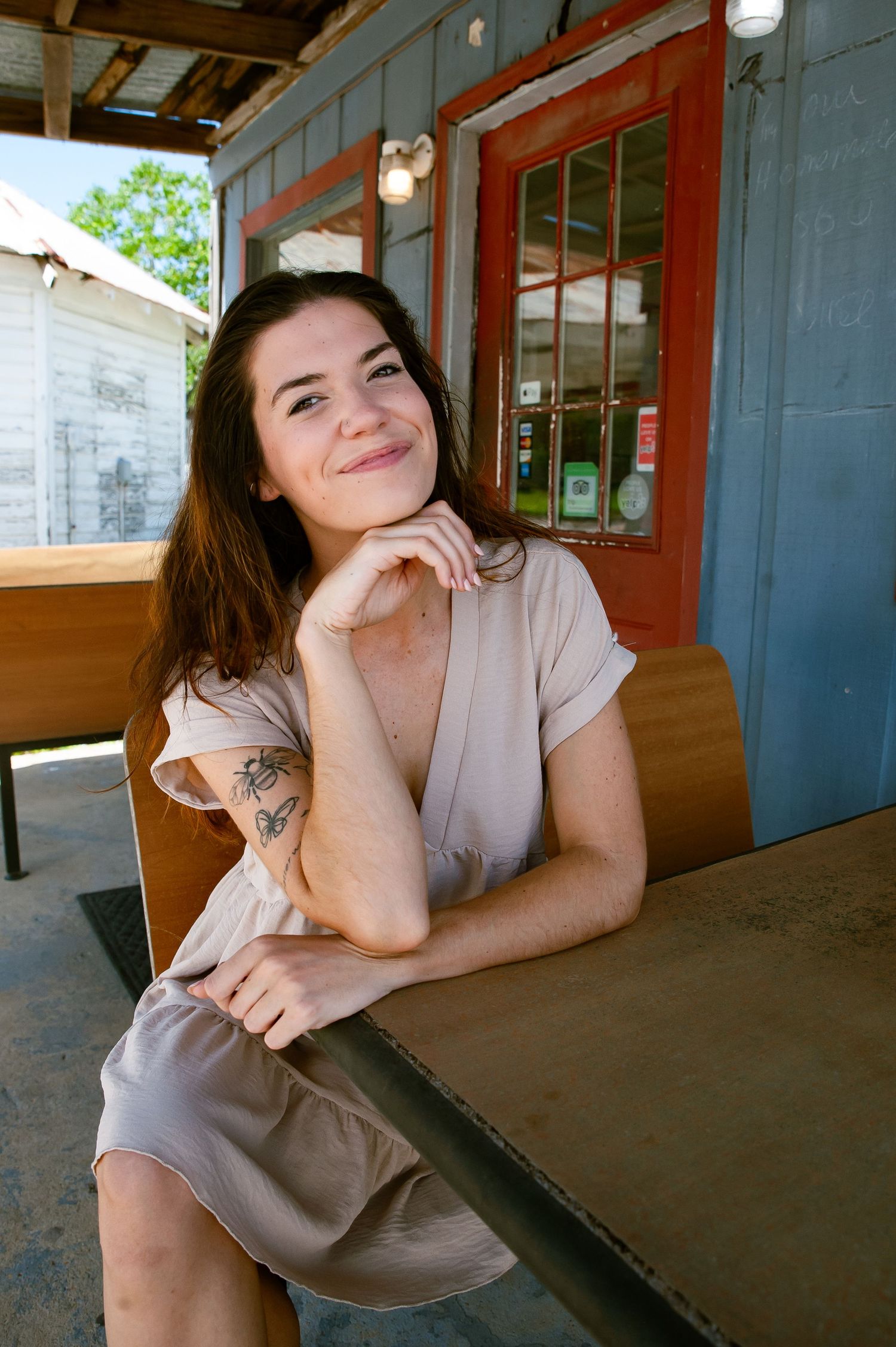 Casual portrait session in beige dress on covered building porch.