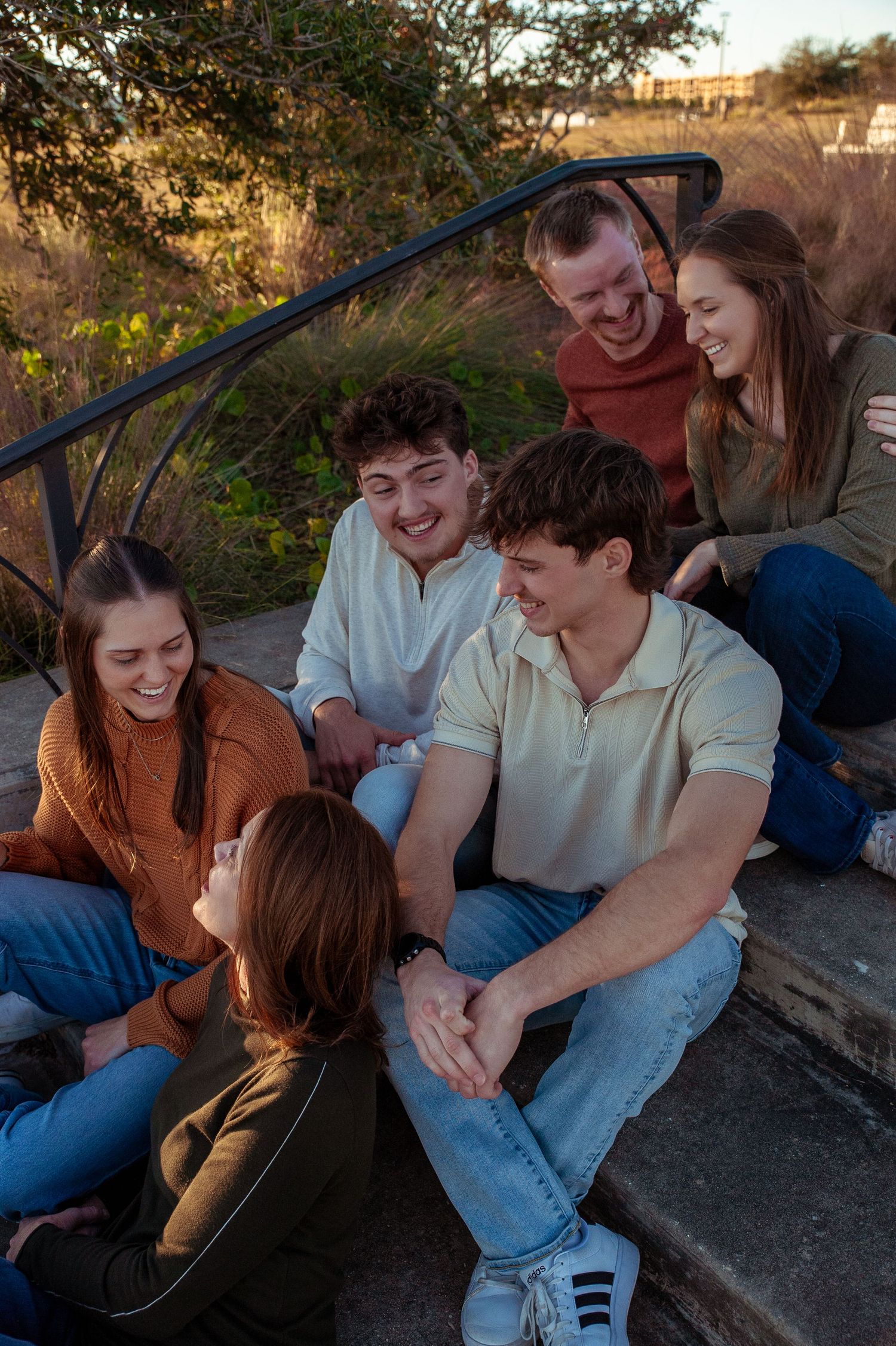 Group of friends sharing laughter and conversation while relaxing outdoors at sunset.