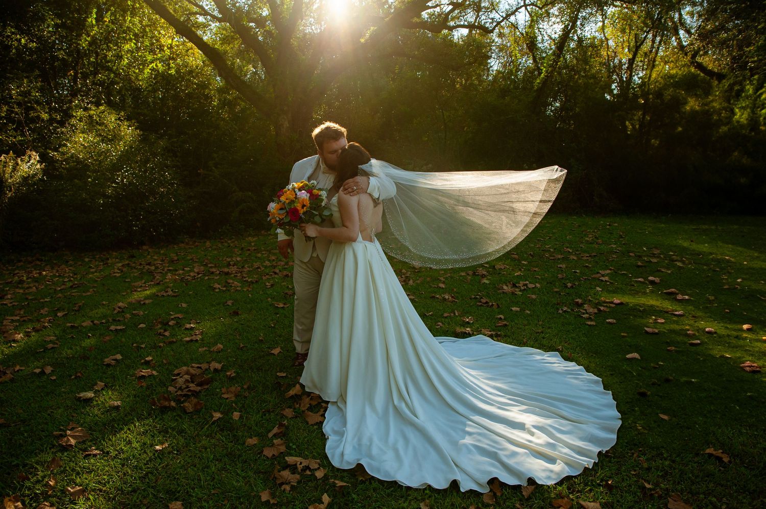 Beautiful white wedding dress flowing in golden sunlight on grassy lawn.