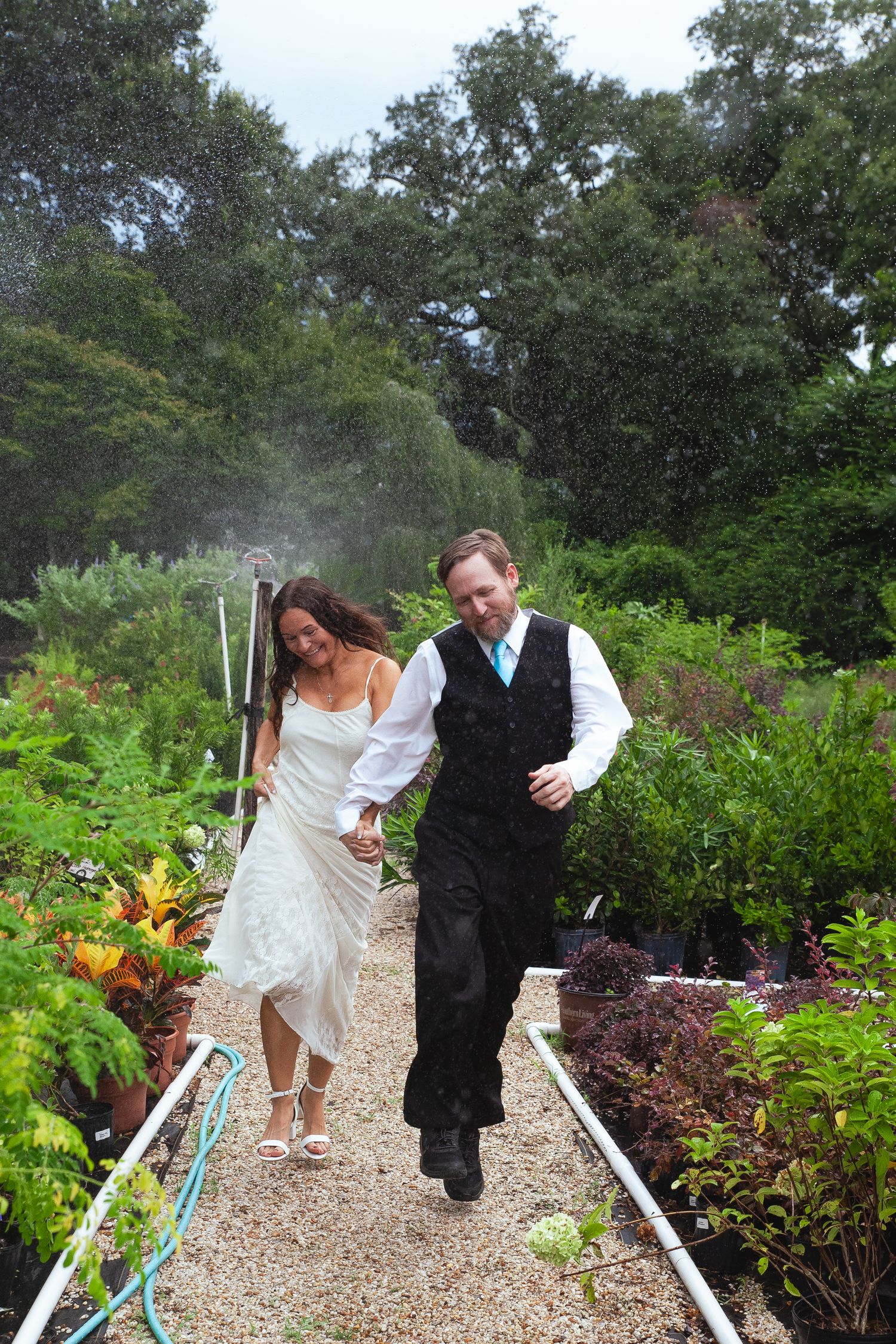 Newlyweds enjoy a romantic moment together on a white gravel pathway bordered by colorful garden plantings.